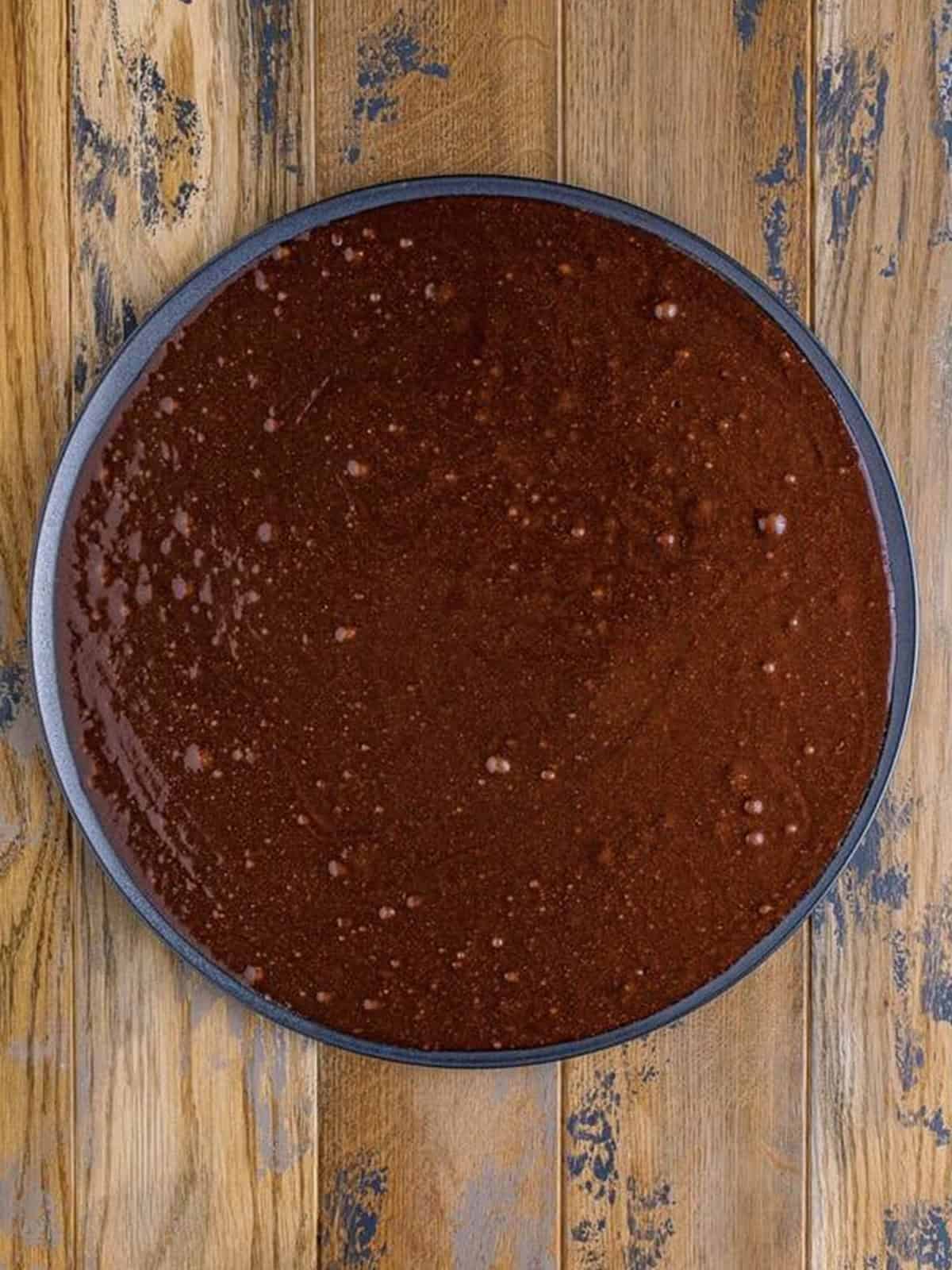 Brownie batter spread evenly onto a greased round pizza pan.