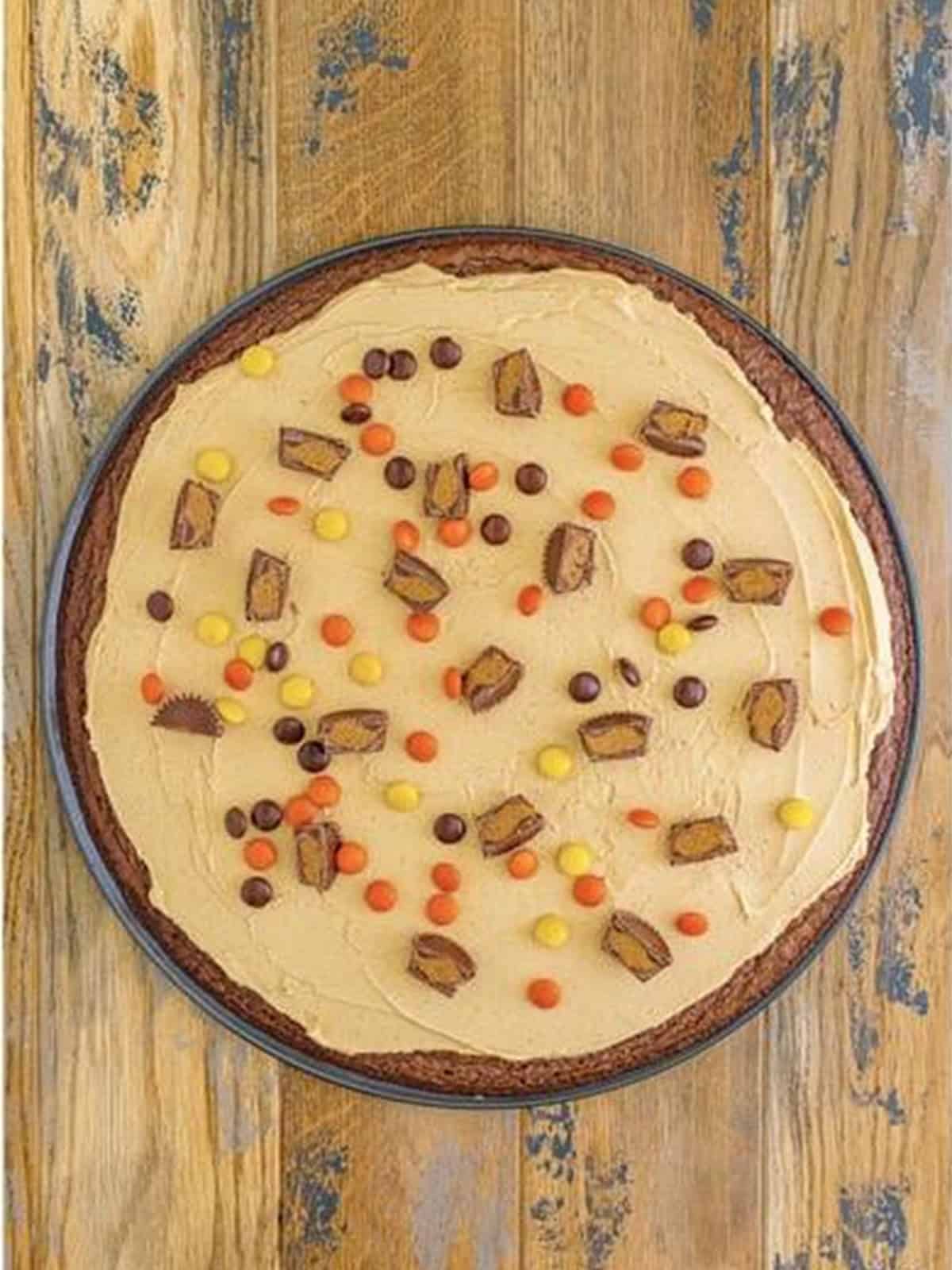 Peanut butter frosting spread over the brownie base and topped with mini peanut butter cups and candy pieces.