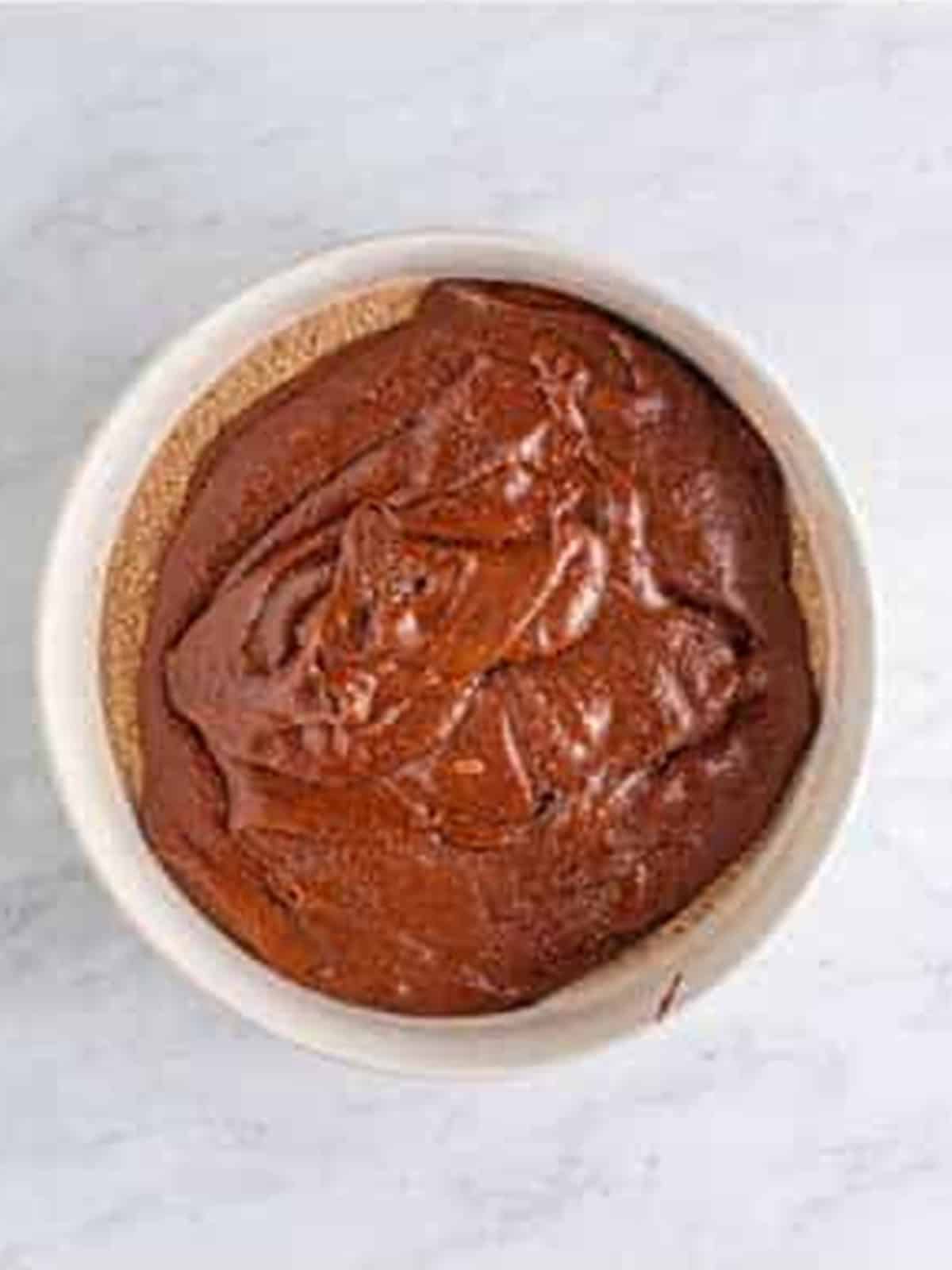Thick fudgy brownie batter combined in a glass mixing bowl.