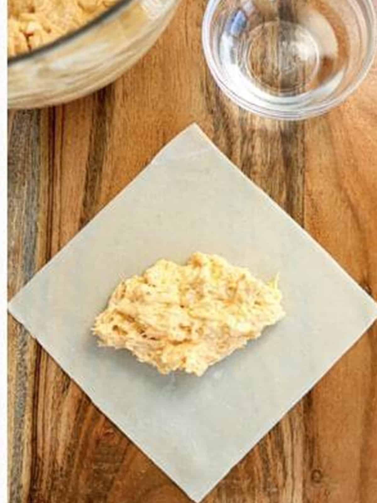 Buffalo chicken filling spooned onto an egg roll wrapper.
