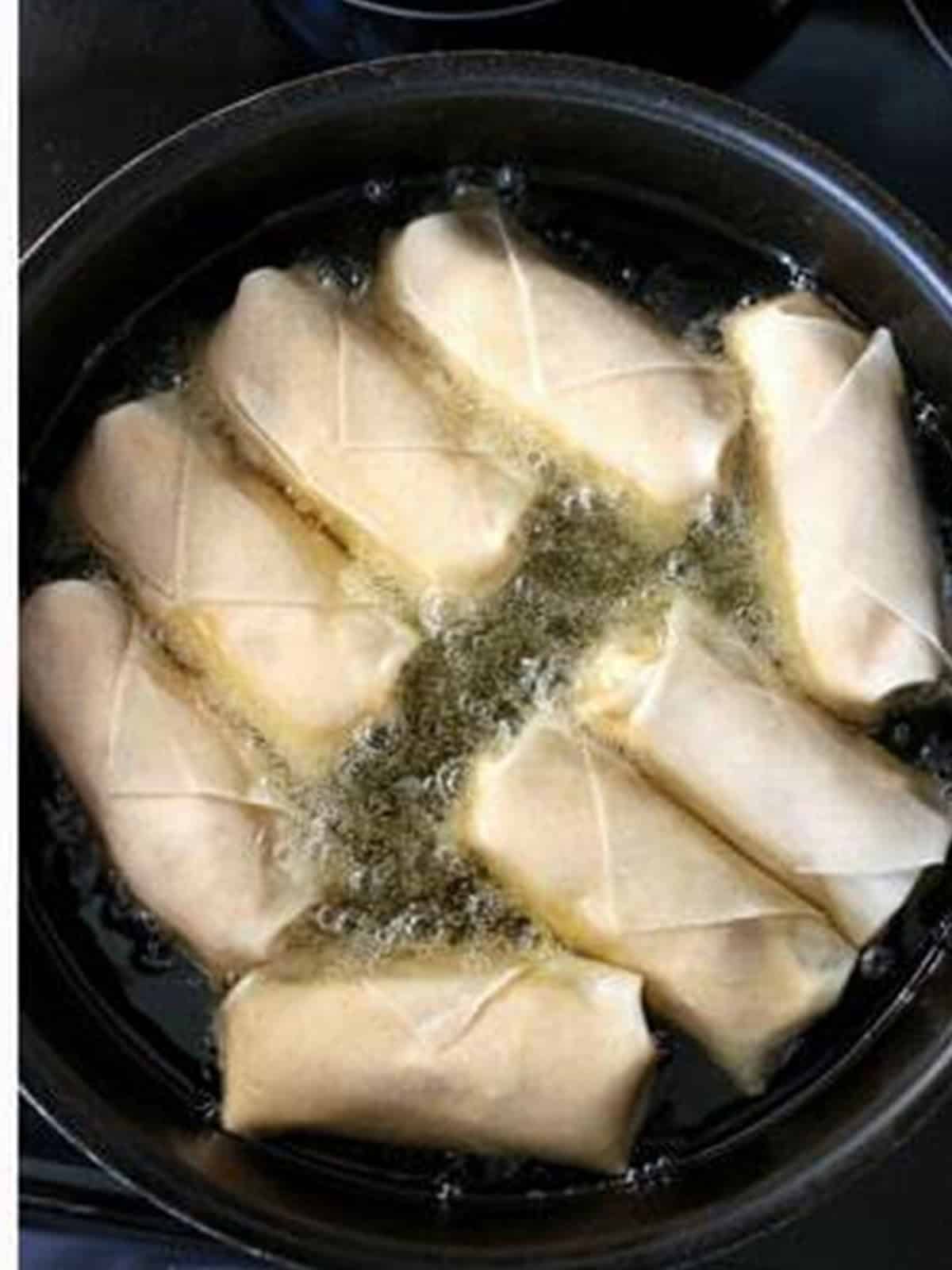 Buffalo chicken egg rolls frying until golden brown.