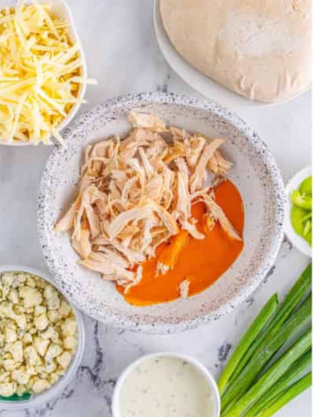 Shredded chicken tossed in buffalo sauce in a bowl.