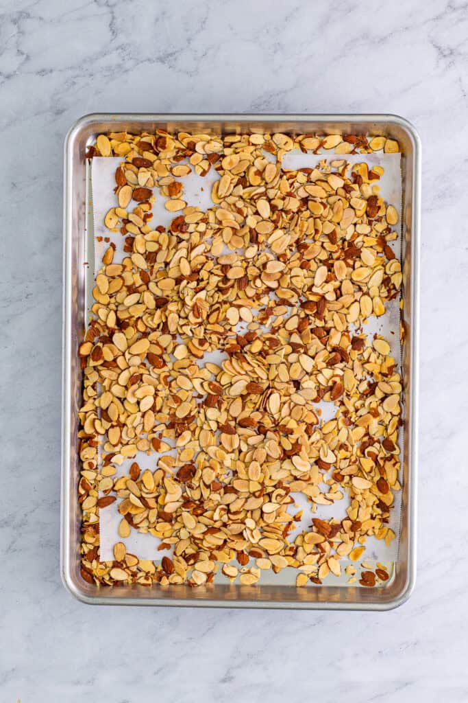 Sliced almonds toasted golden on a sheet tray for almond torte cake.