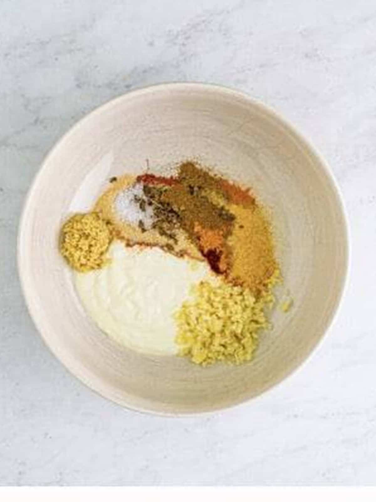 Yogurt, ginger, garlic, and Indian spices added to a bowl to make the butter chicken marinade.