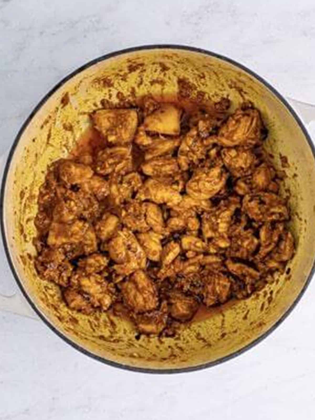 Marinated chicken browned in ghee in a Dutch oven for butter chicken.