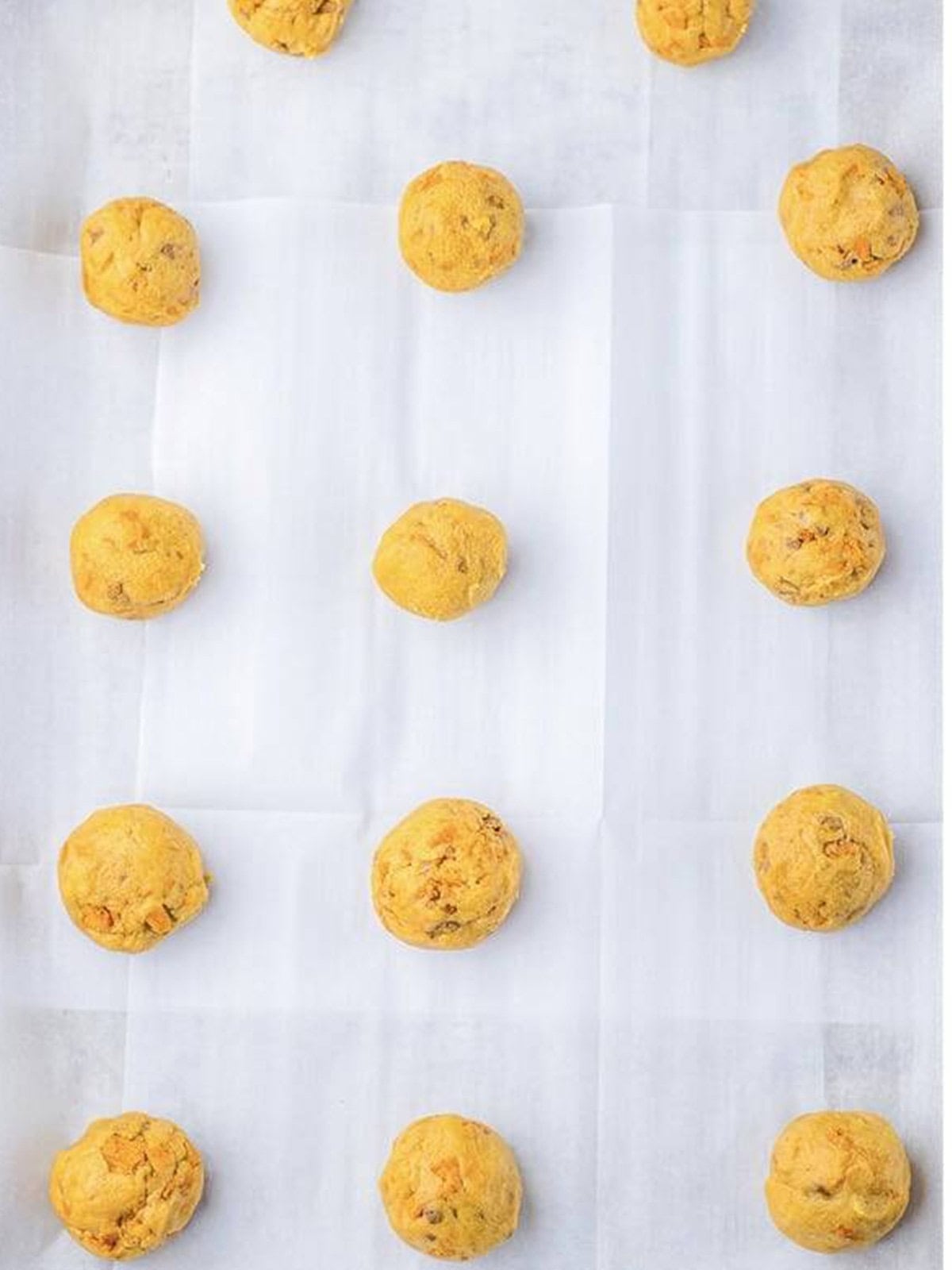 Rolled butterfinger cookie dough balls on a parchment-lined baking sheet.