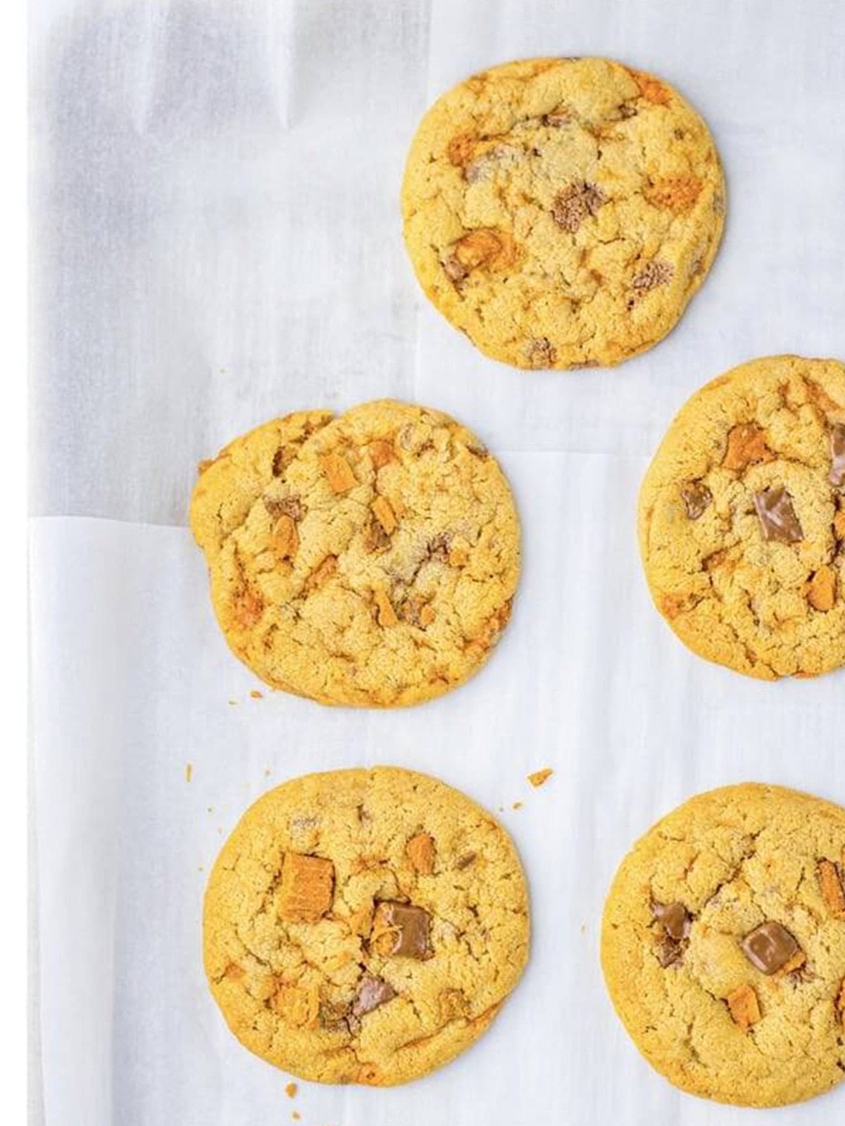 Baked butterfinger cookies on a parchment-lined sheet.