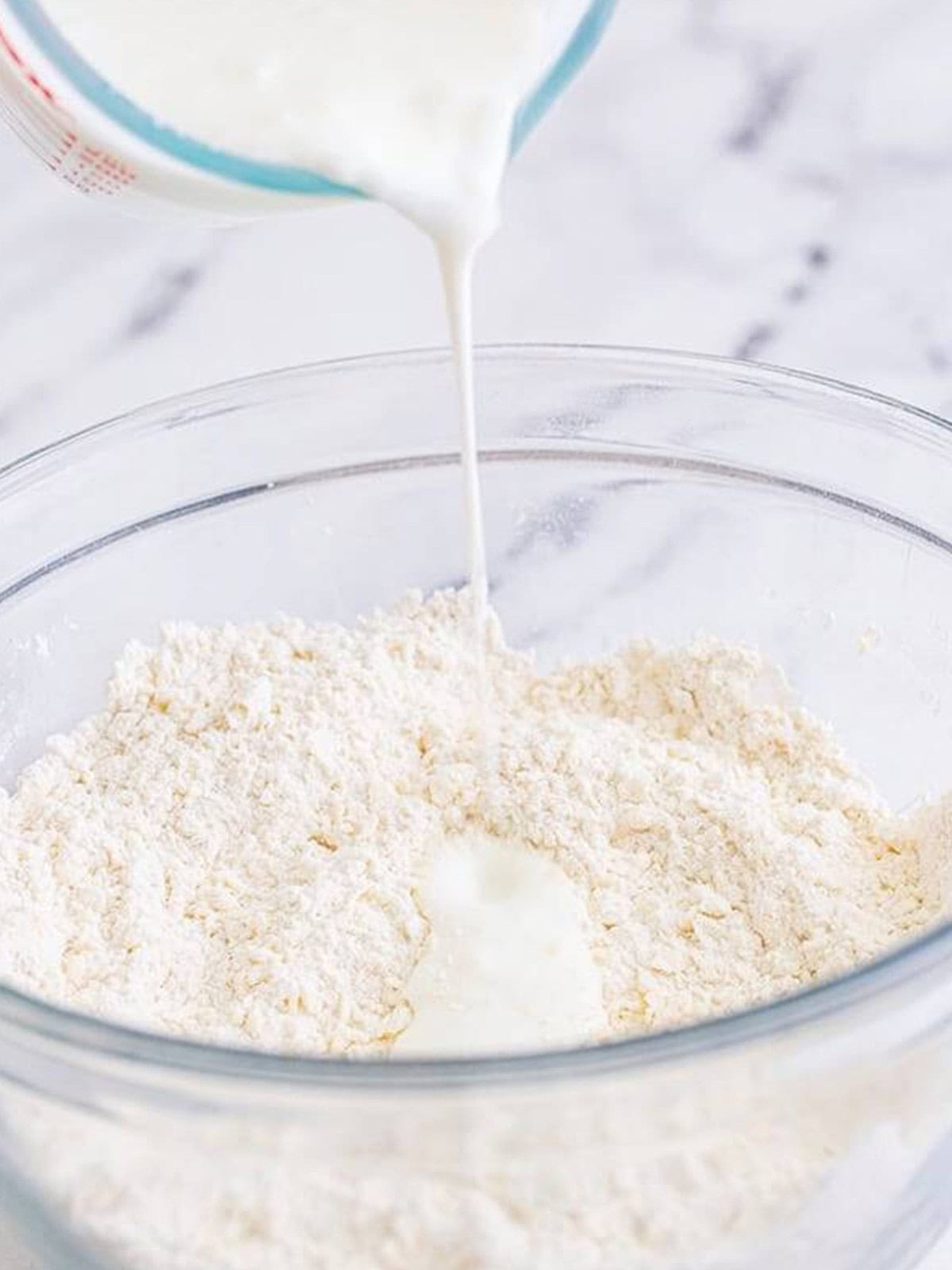 Pouring buttermilk into the flour mixture for buttermilk biscuits.