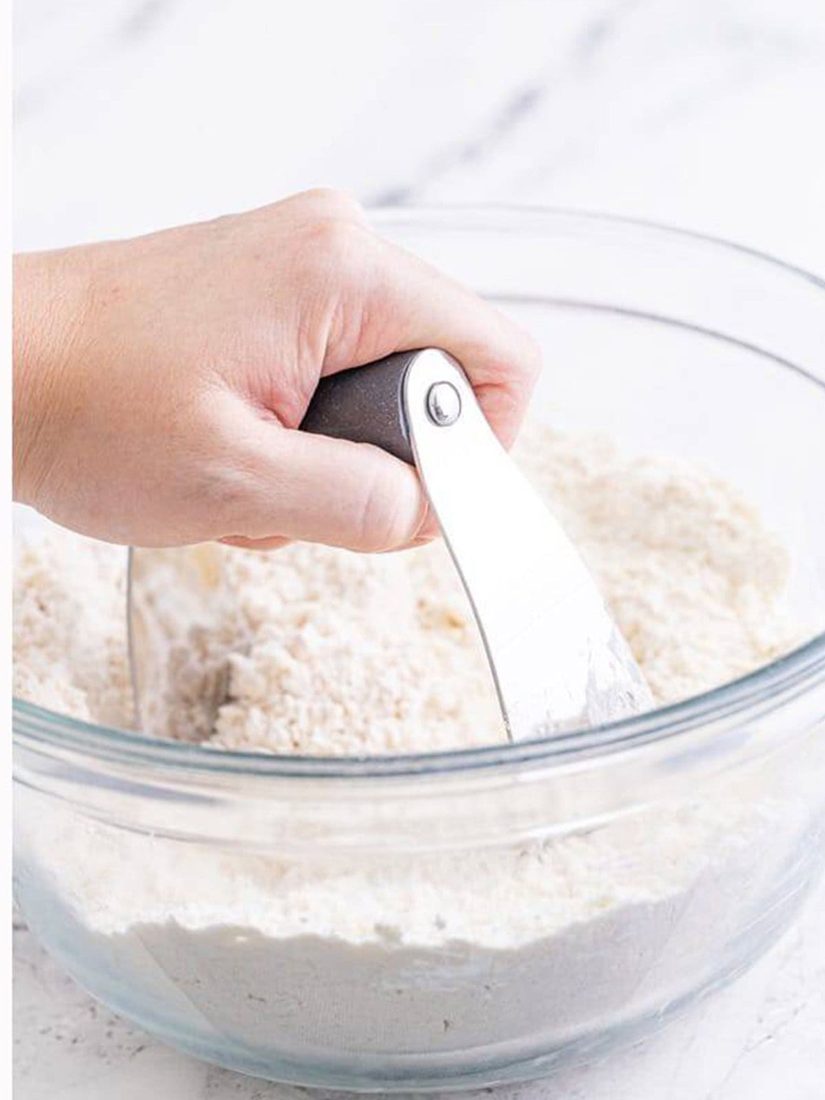 Cutting cold butter into the flour for buttermilk biscuits until crumbly.