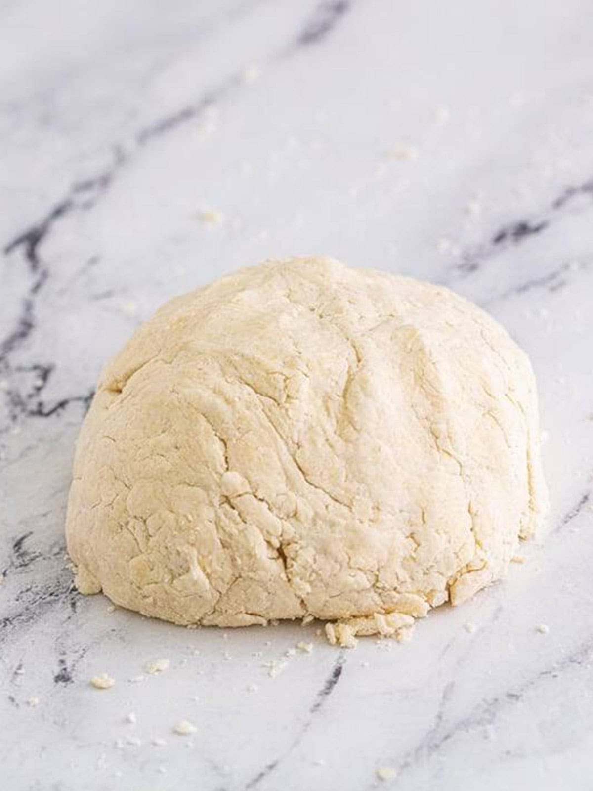 Buttermilk biscuit dough formed into a ball on a floured surface.
