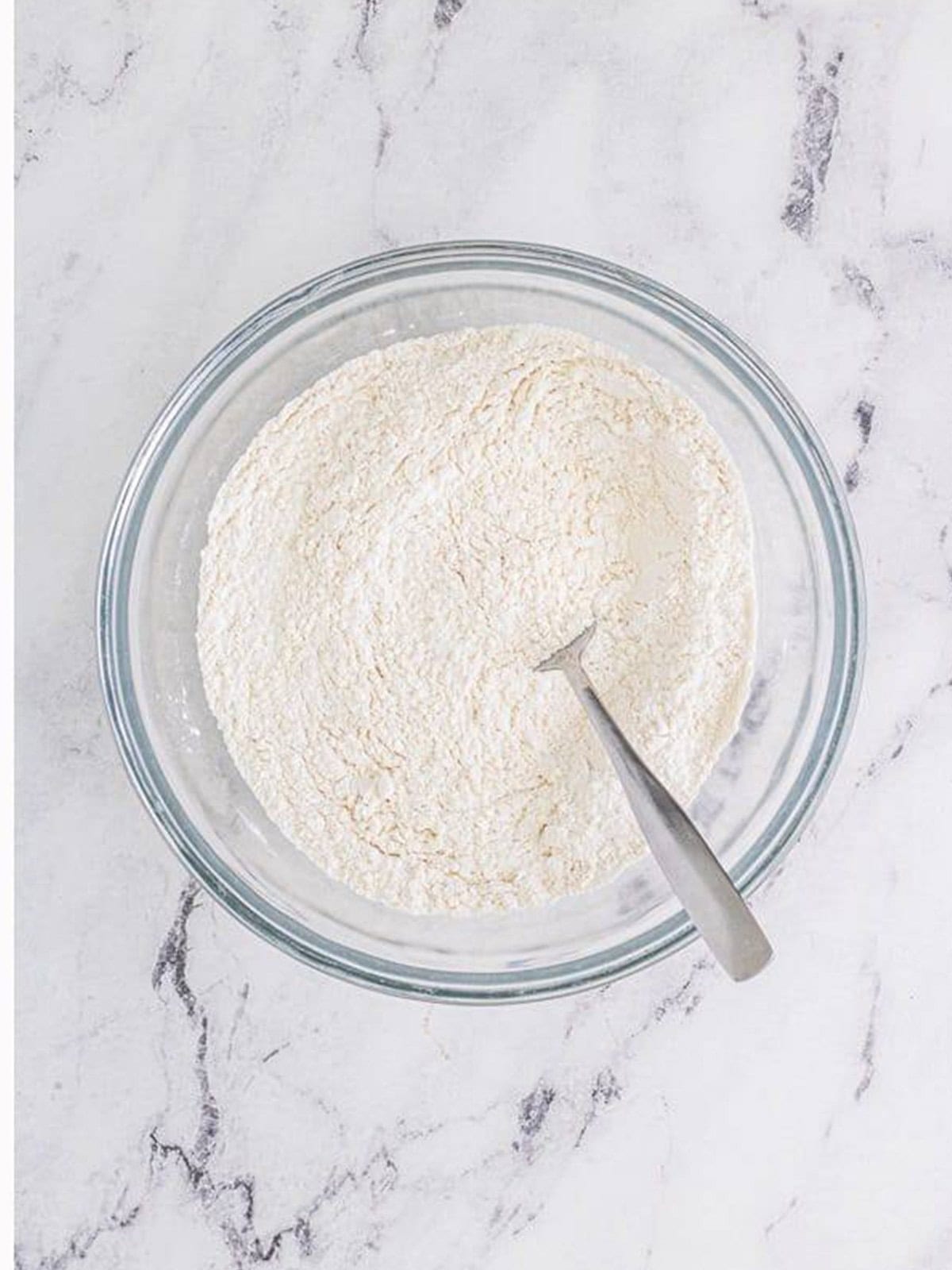 Dry ingredients for buttermilk biscuits whisked together in a glass bowl.