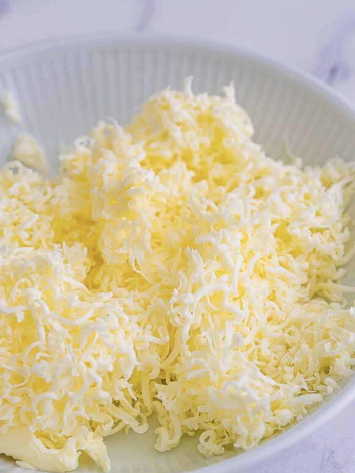 Grated frozen butter for buttermilk biscuits in a white bowl.