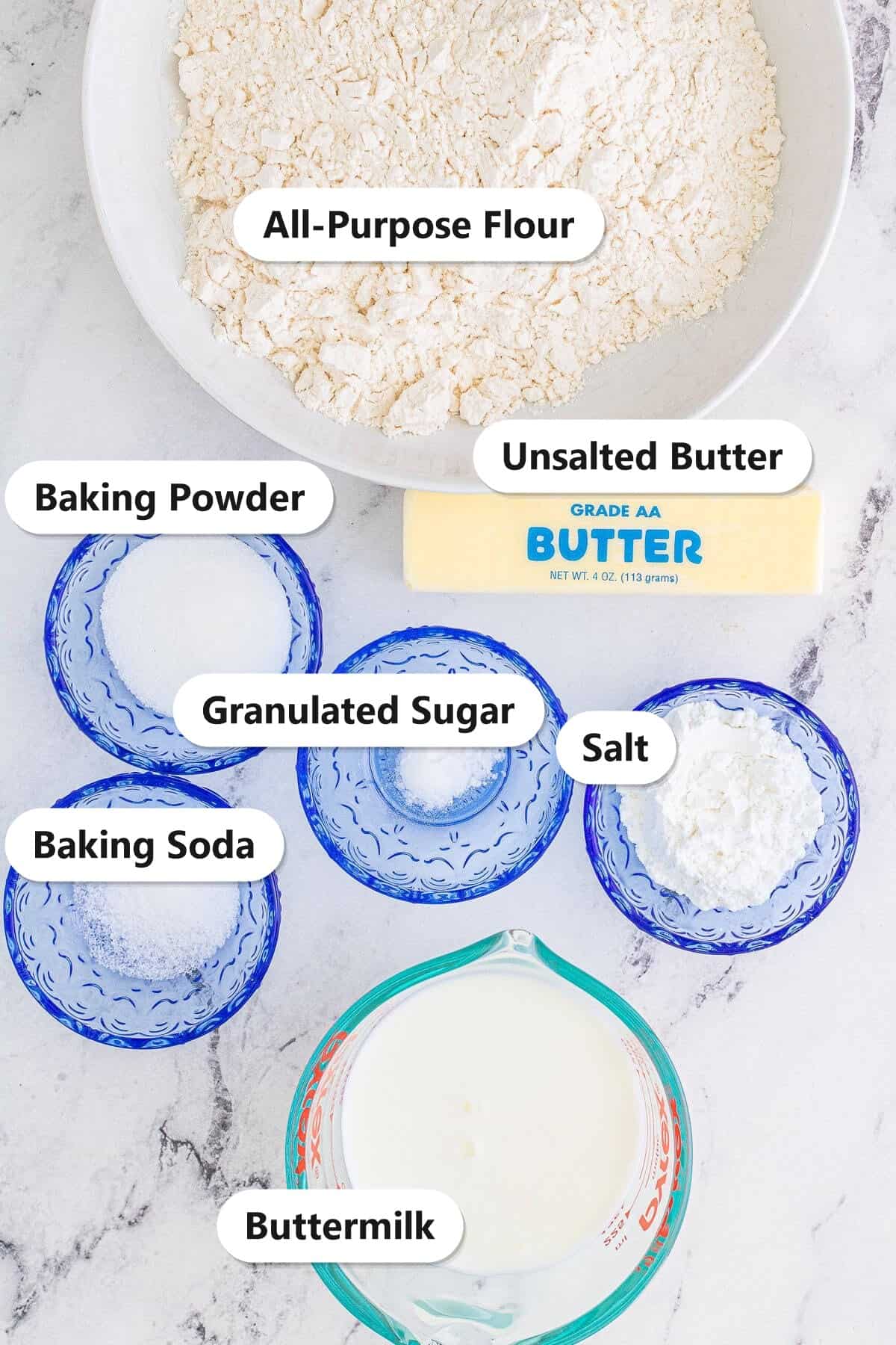 Labeled ingredients for buttermilk biscuits including all-purpose flour, unsalted butter, baking powder, sugar, salt, baking soda, and buttermilk.