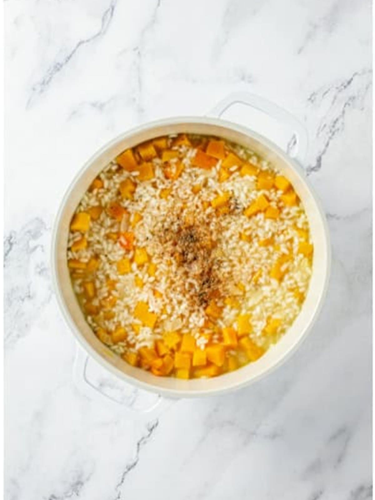 Adding broth and black pepper to the butternut squash risotto.