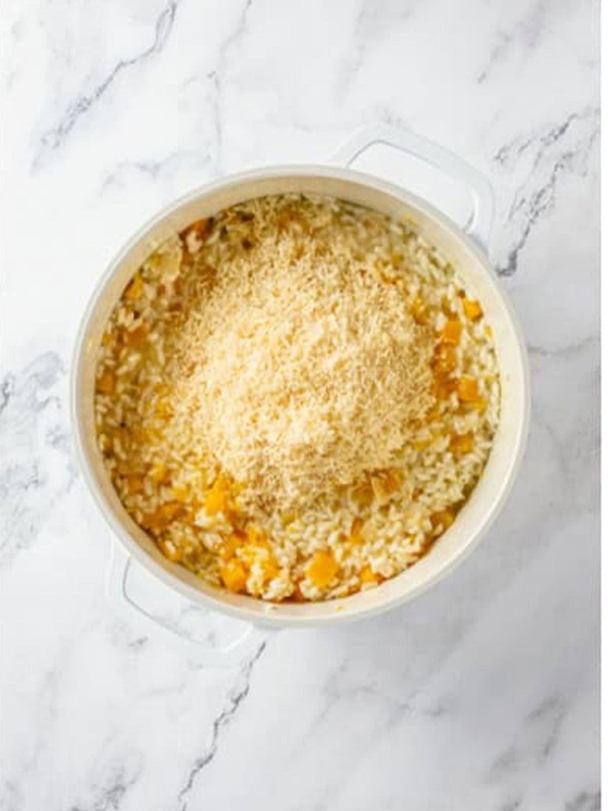 Stirring grated parmesan into the finished butternut squash risotto.