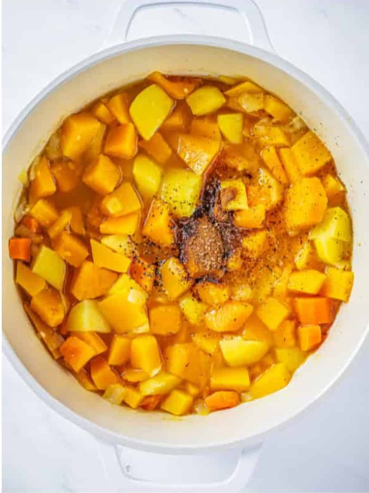 Cinnamon, nutmeg, salt, and pepper added to the simmered butternut squash soup vegetables.