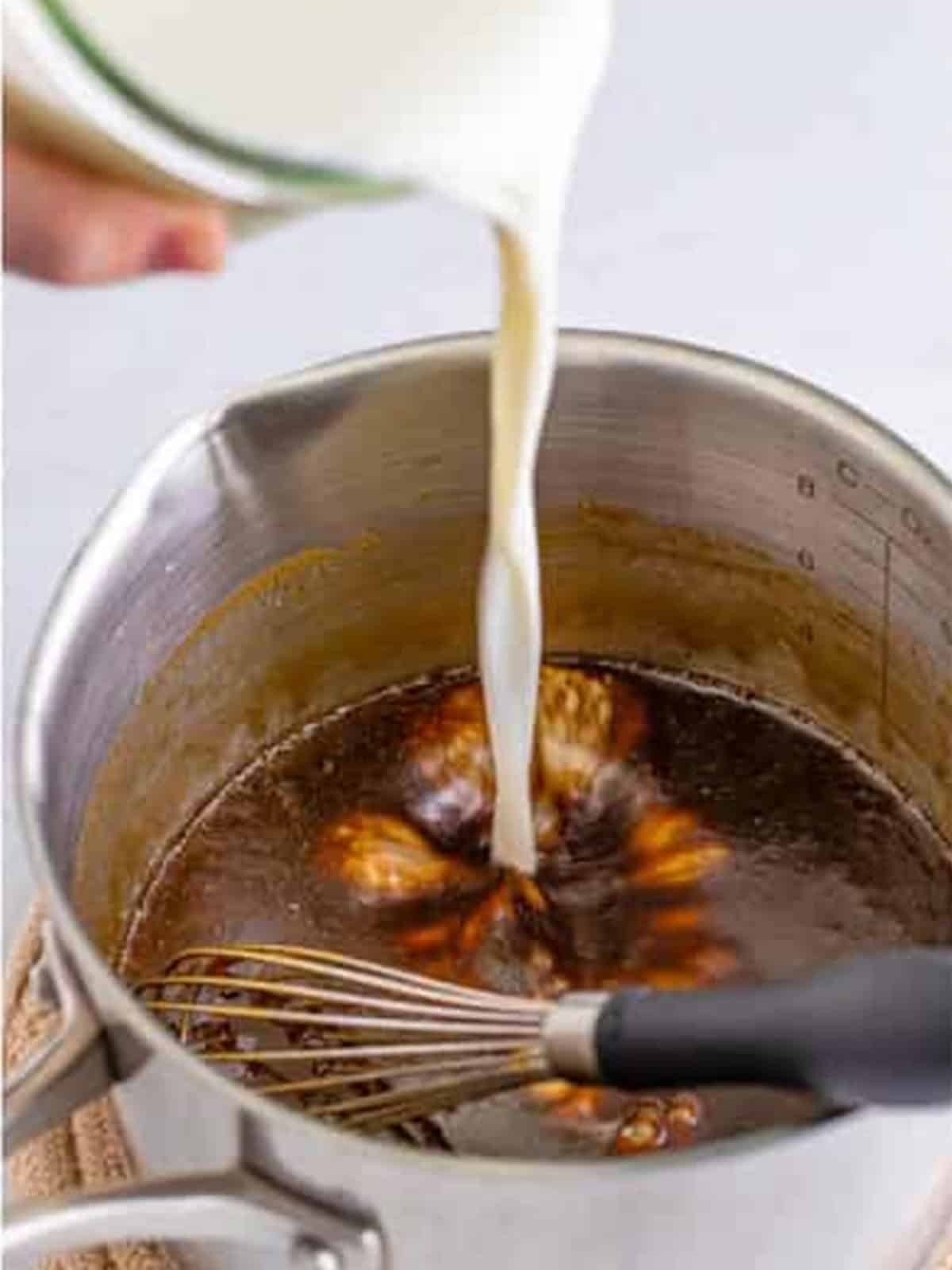 Whisking milk into the butterscotch base in a saucepan.
