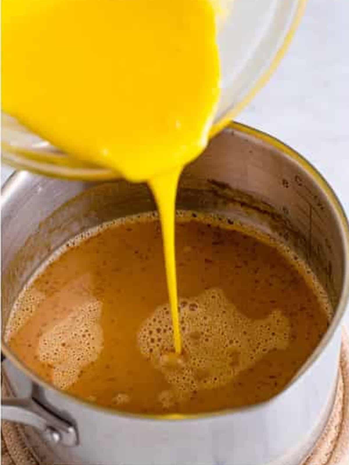Streaming the egg mixture into the butterscotch custard while whisking.