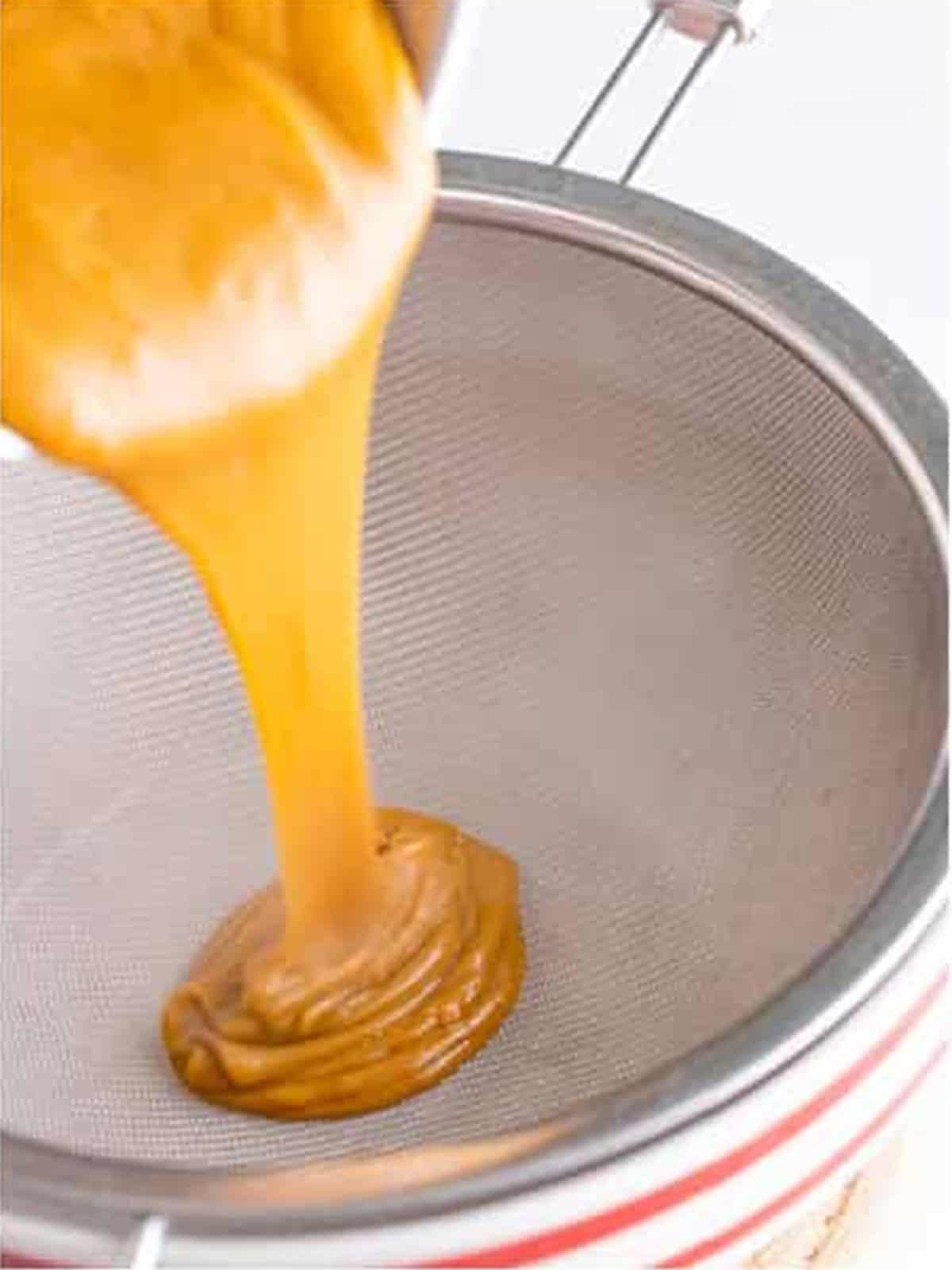 Pouring the butterscotch custard through a fine mesh strainer.