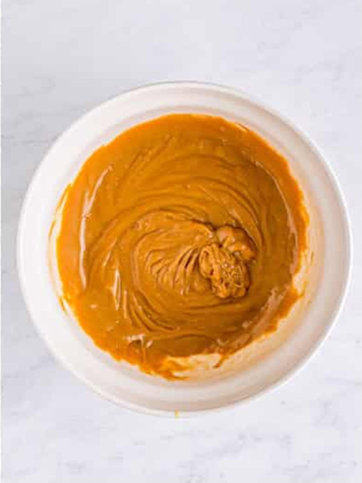 Smooth butterscotch custard in a bowl after stirring in vanilla.