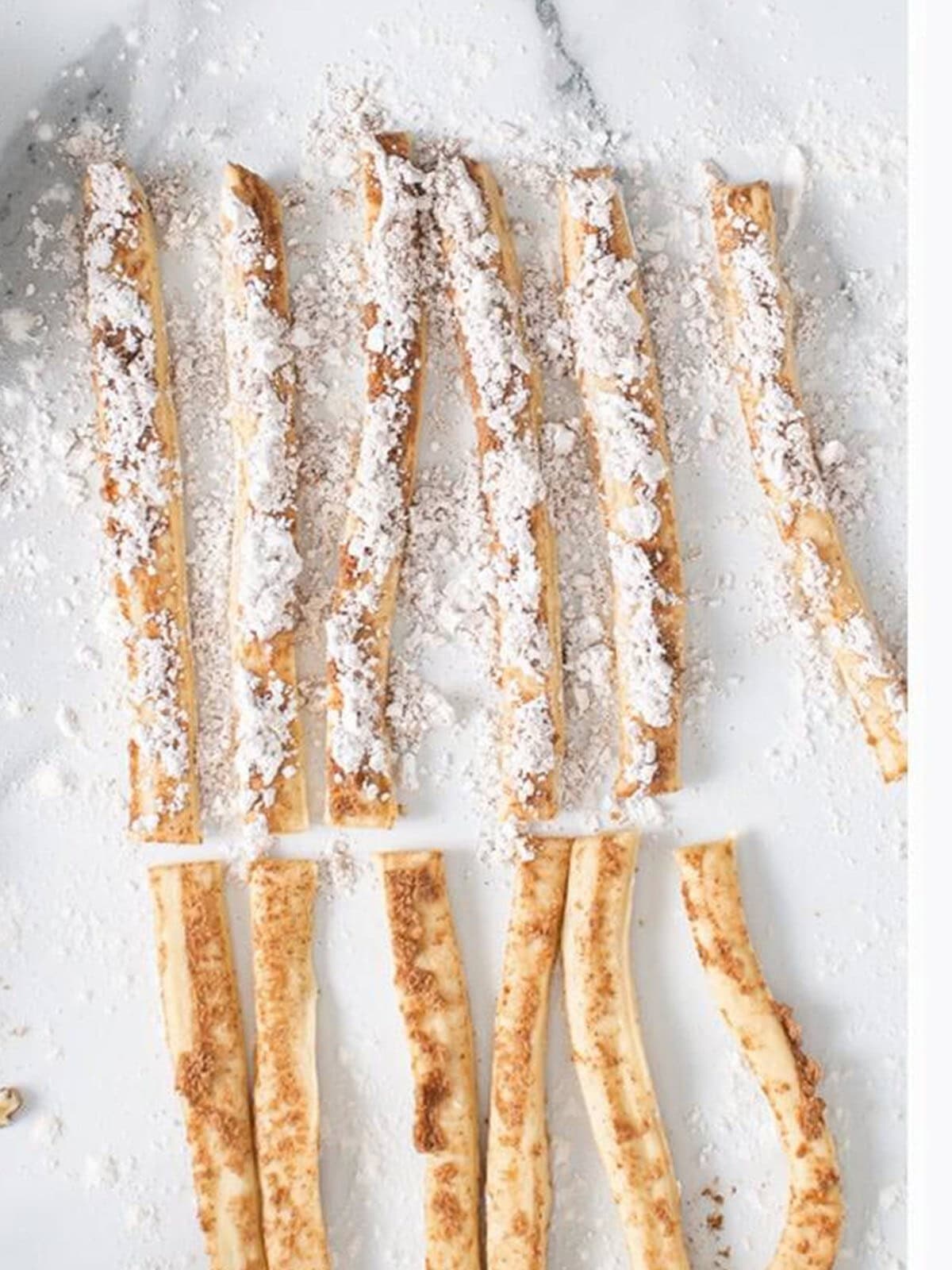 Cinnamon roll strips sprinkled with cinnamon and powdered sugar.