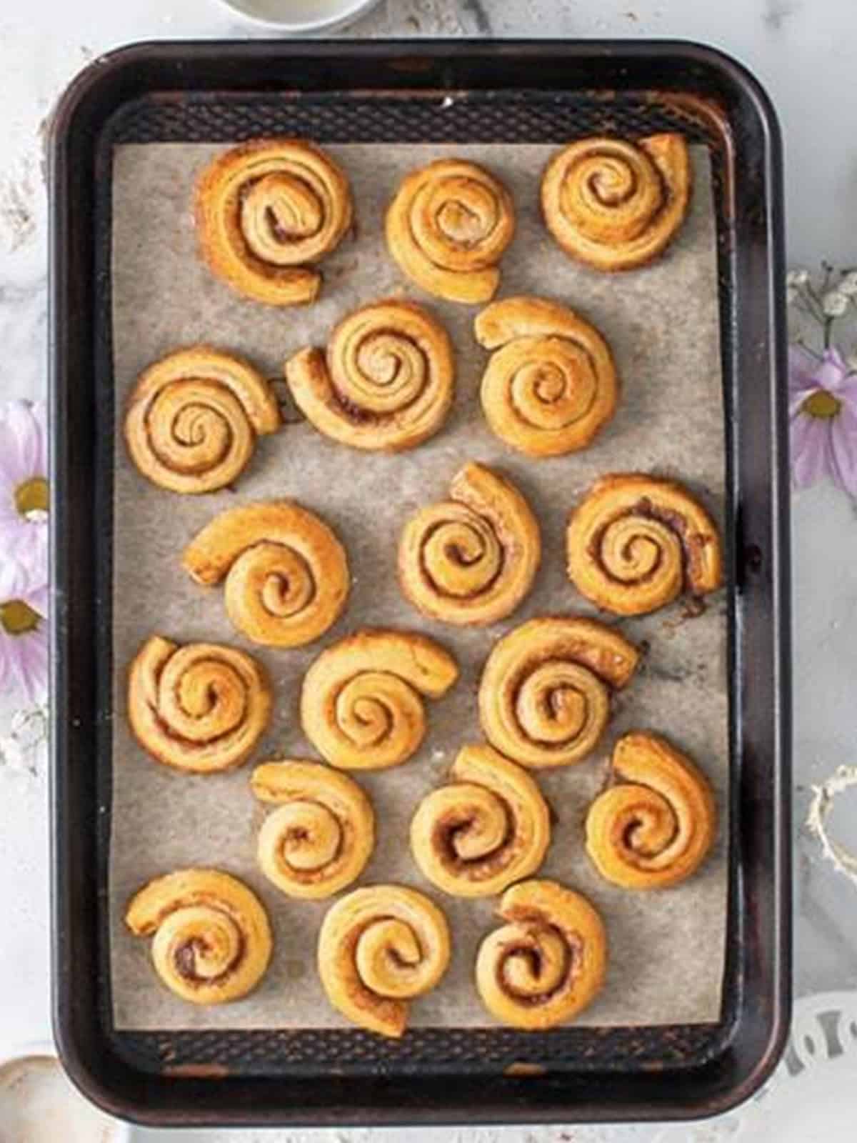 Baked golden Mini Cinnamon Rolls on a baking sheet.