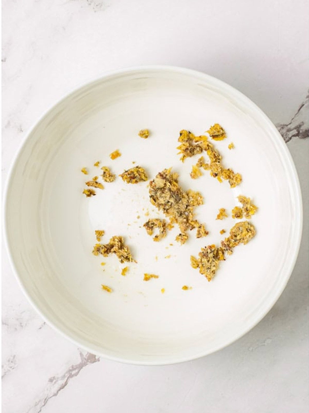 A smoked sardine and garlic mashed into a paste in a bowl to start the Caesar salad dressing.