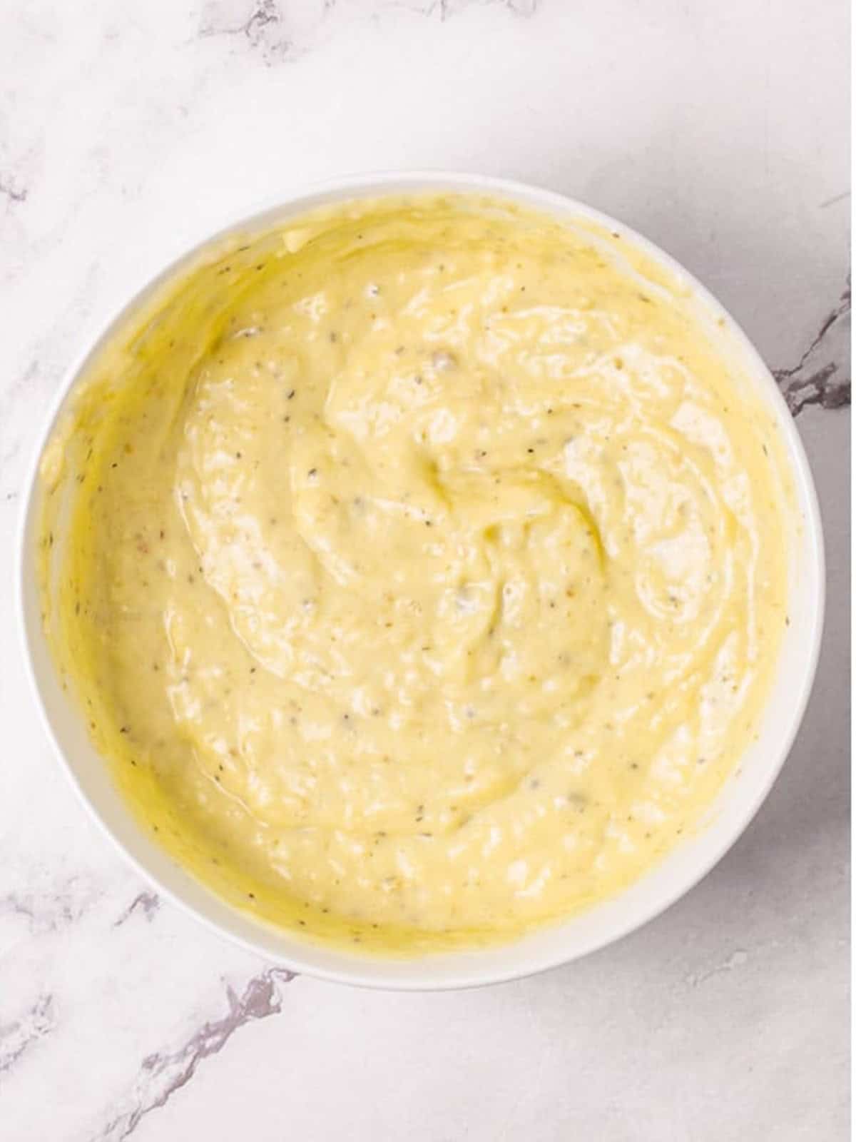 Finished creamy homemade Caesar salad dressing whisked smooth in a bowl.