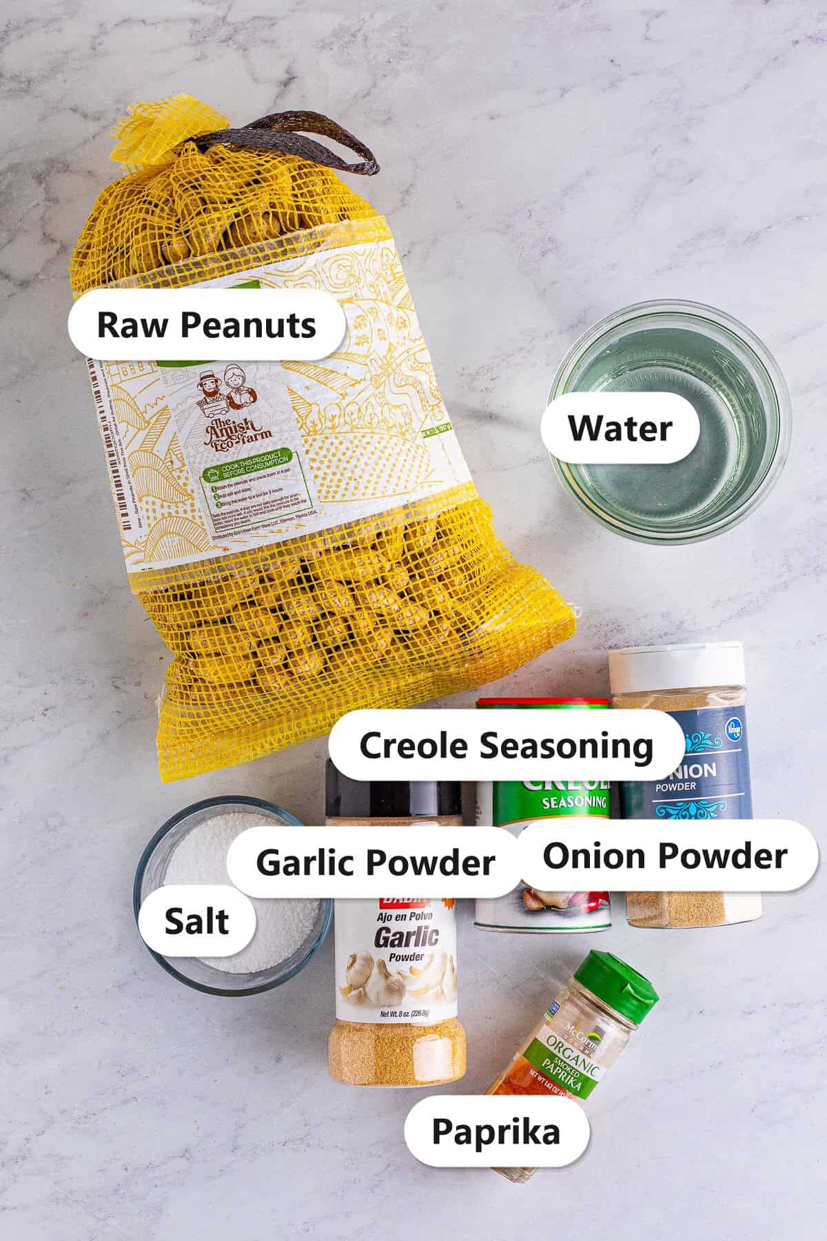 Labeled ingredients to make Cajun boiled peanuts including raw peanuts in shell, water, salt, garlic powder, Creole seasoning, onion powder, and paprika.