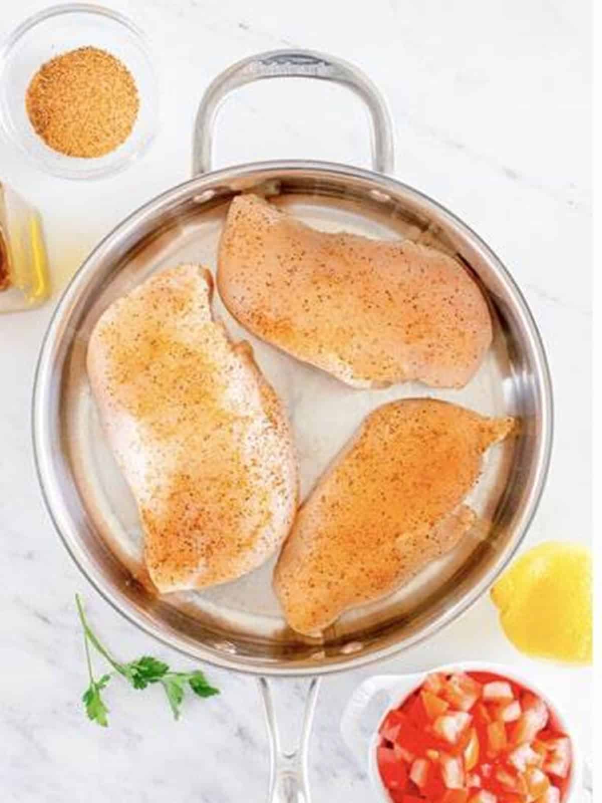 Seasoned chicken breasts searing in a skillet for Cajun Chicken Pasta.