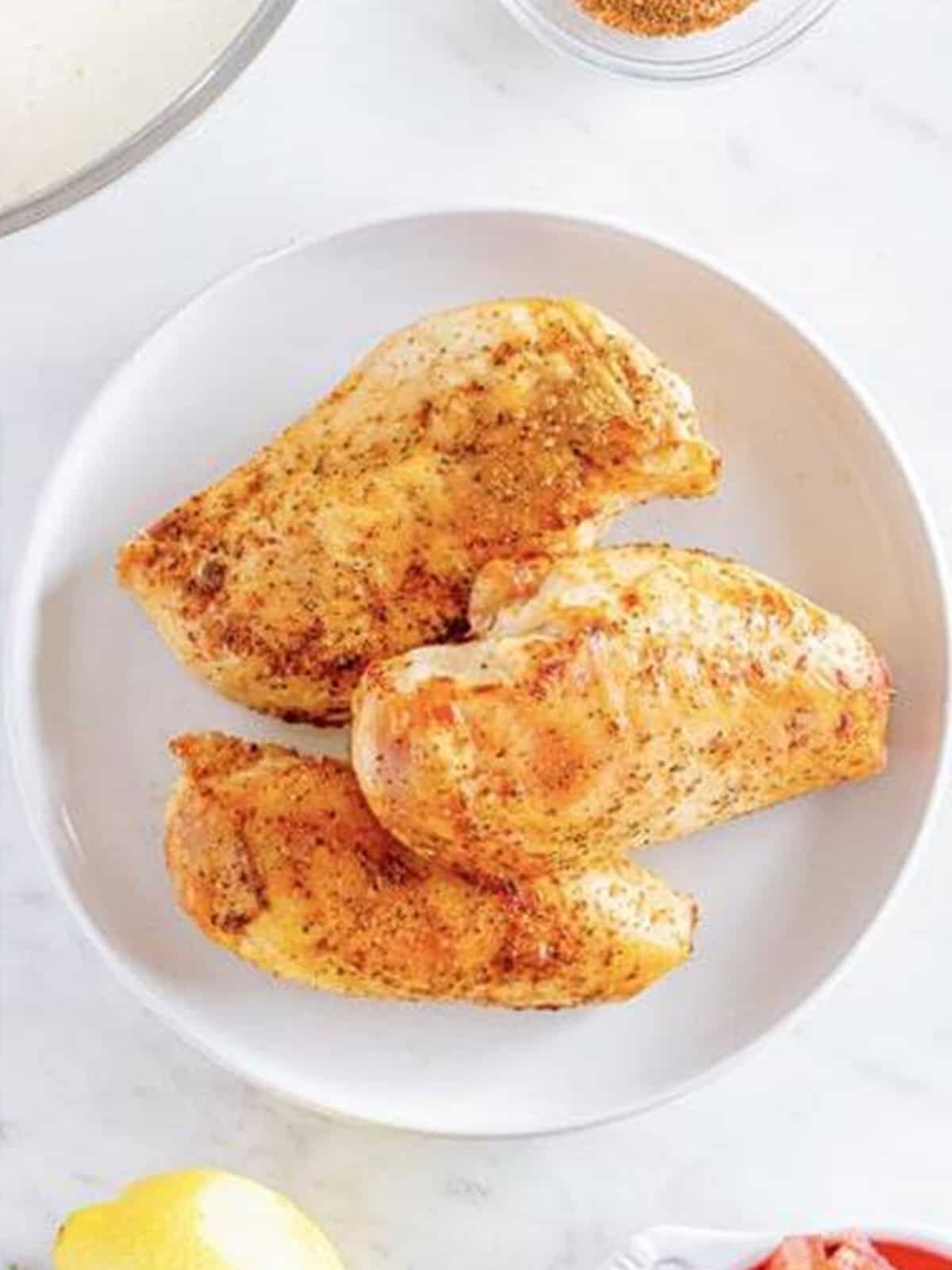 Cooked cajun chicken breasts resting on a white plate for Cajun Chicken Pasta.