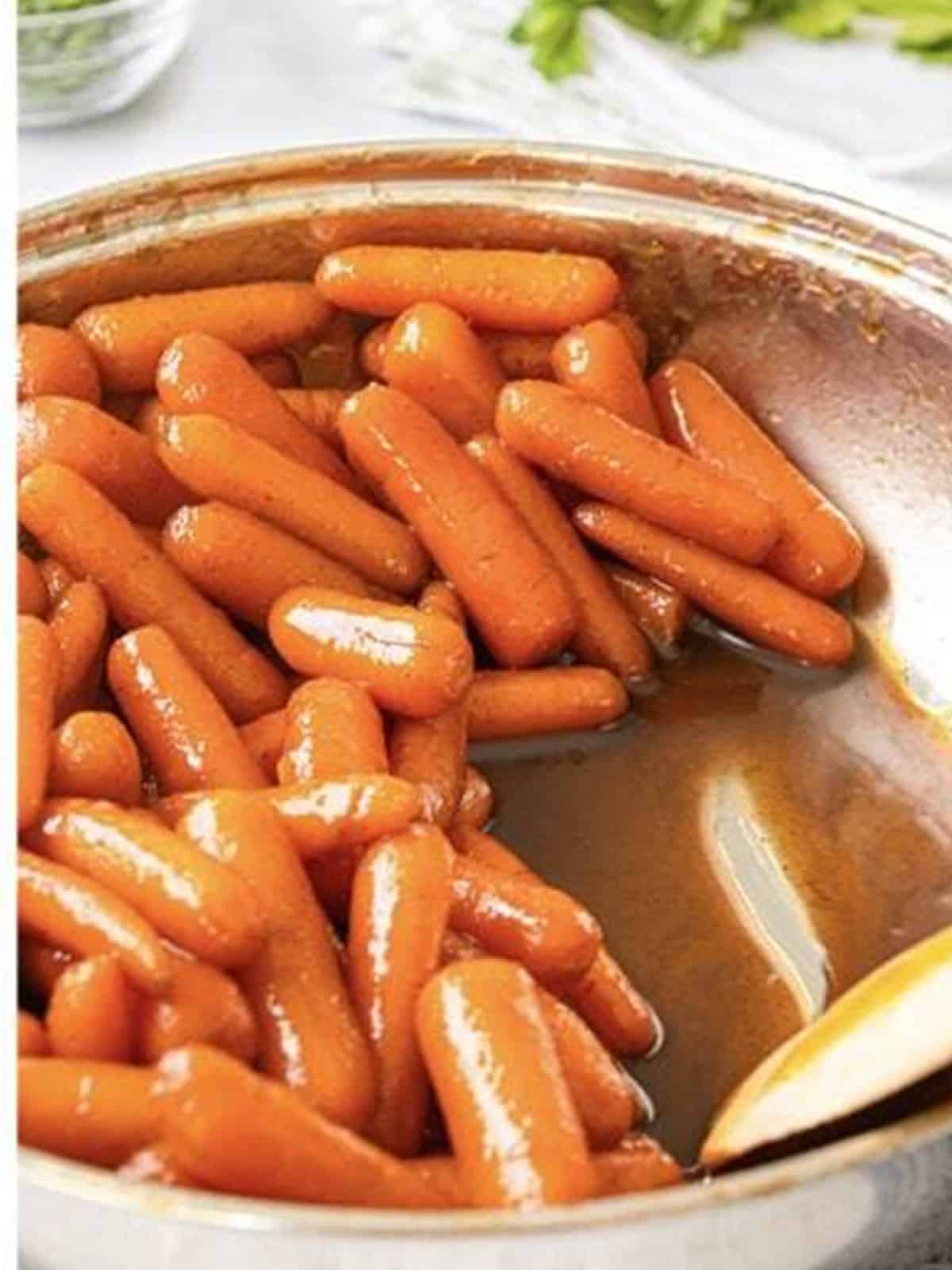 Glossy candied carrots coated in a thick brown sugar glaze in a pan.