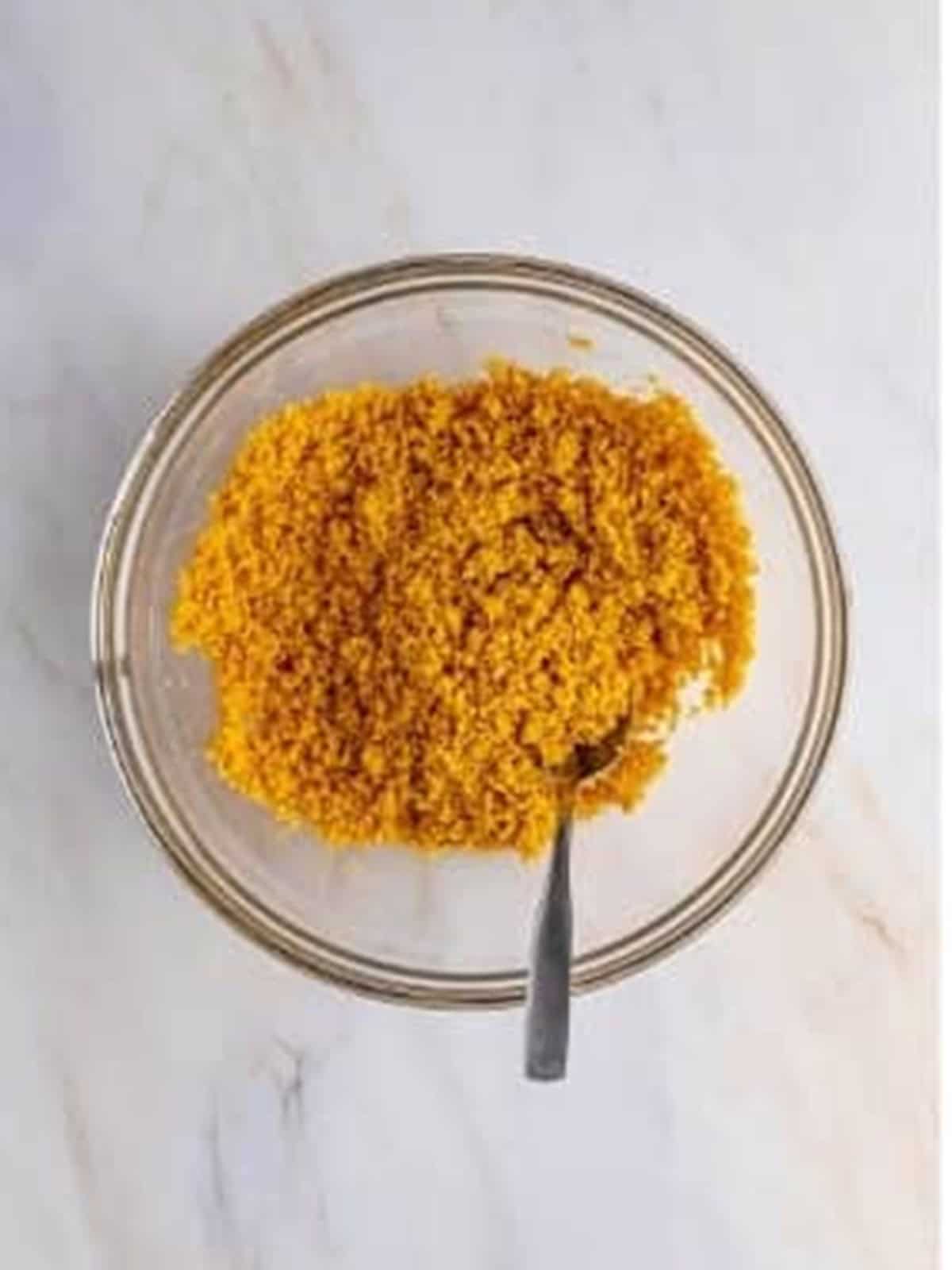 Graham cracker crumbs, butter, and sugar stirred in a bowl for cannoli pie crust.