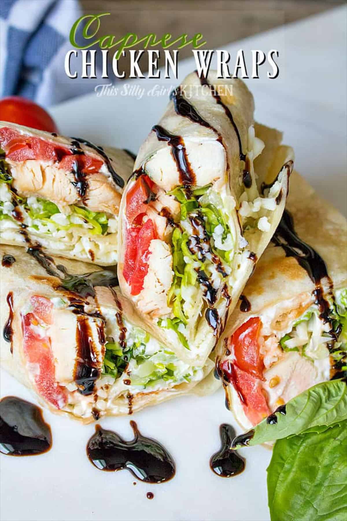 Stacked caprese chicken wraps cut in half showing chicken, tomato, basil, and balsamic glaze.