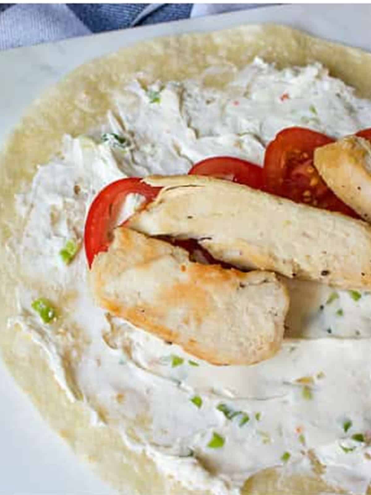 A flour tortilla spread with Italian cream cheese and layered with sliced chicken and tomatoes.
