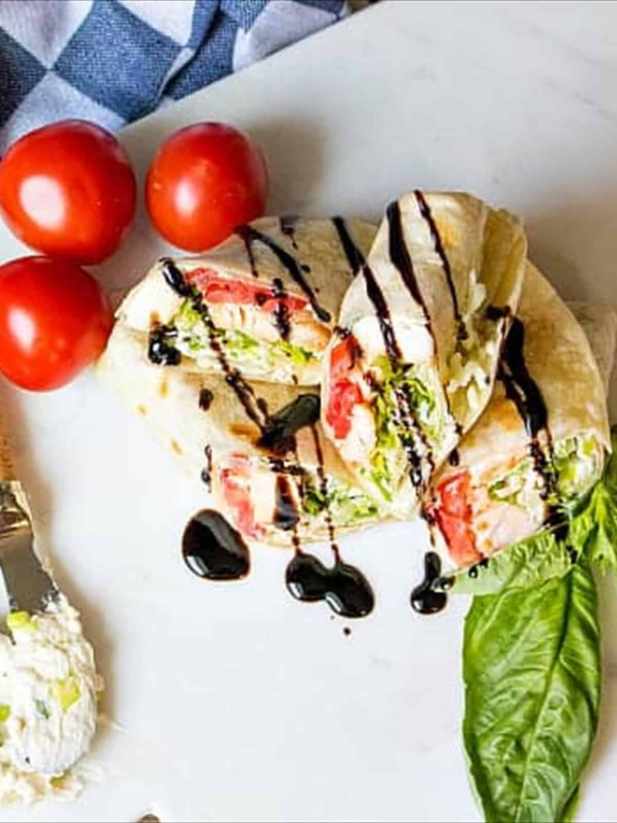 A finished caprese chicken wrap drizzled with balsamic glaze.