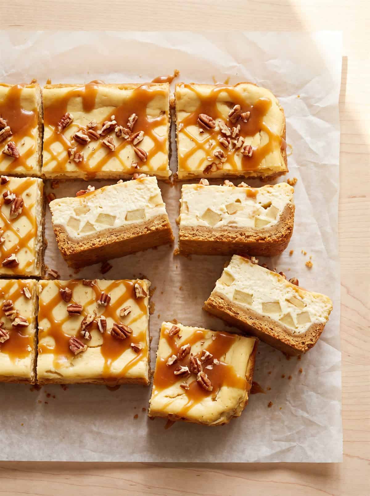 Caramel apple cheesecake bars cut into squares with caramel drizzle.