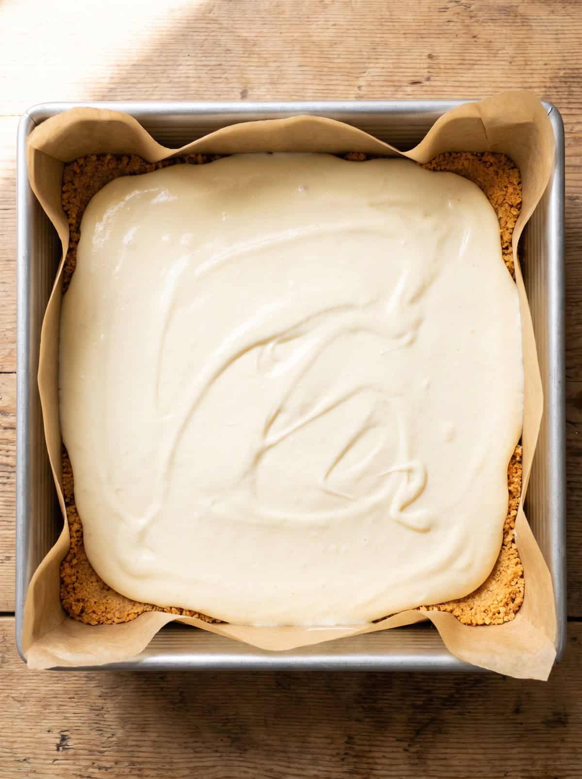 Creamy cheesecake batter spread over a cookie crust in a baking pan.