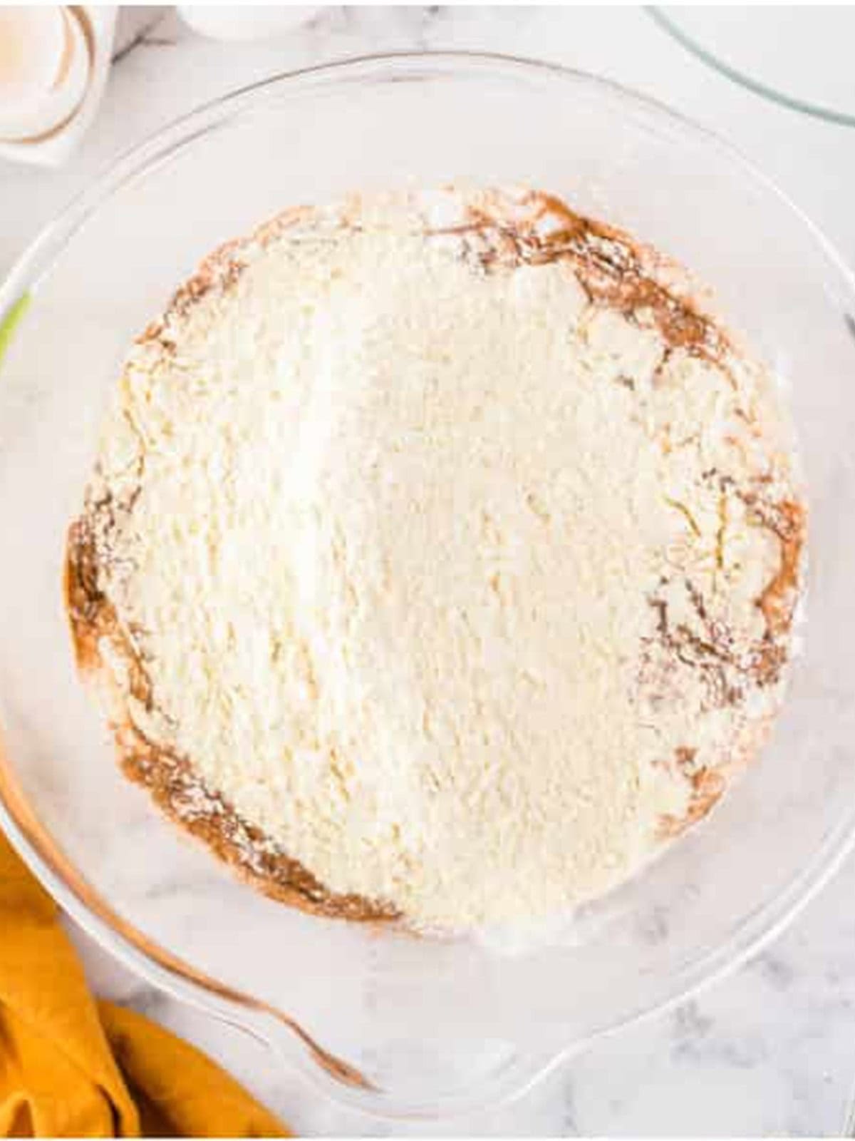 Flour, baking powder, and spices added to the wet ingredients for funnel cake batter.