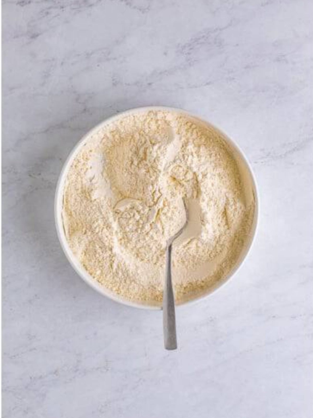 Flour, baking powder, baking soda, and salt whisked together in a bowl for caramel cake.