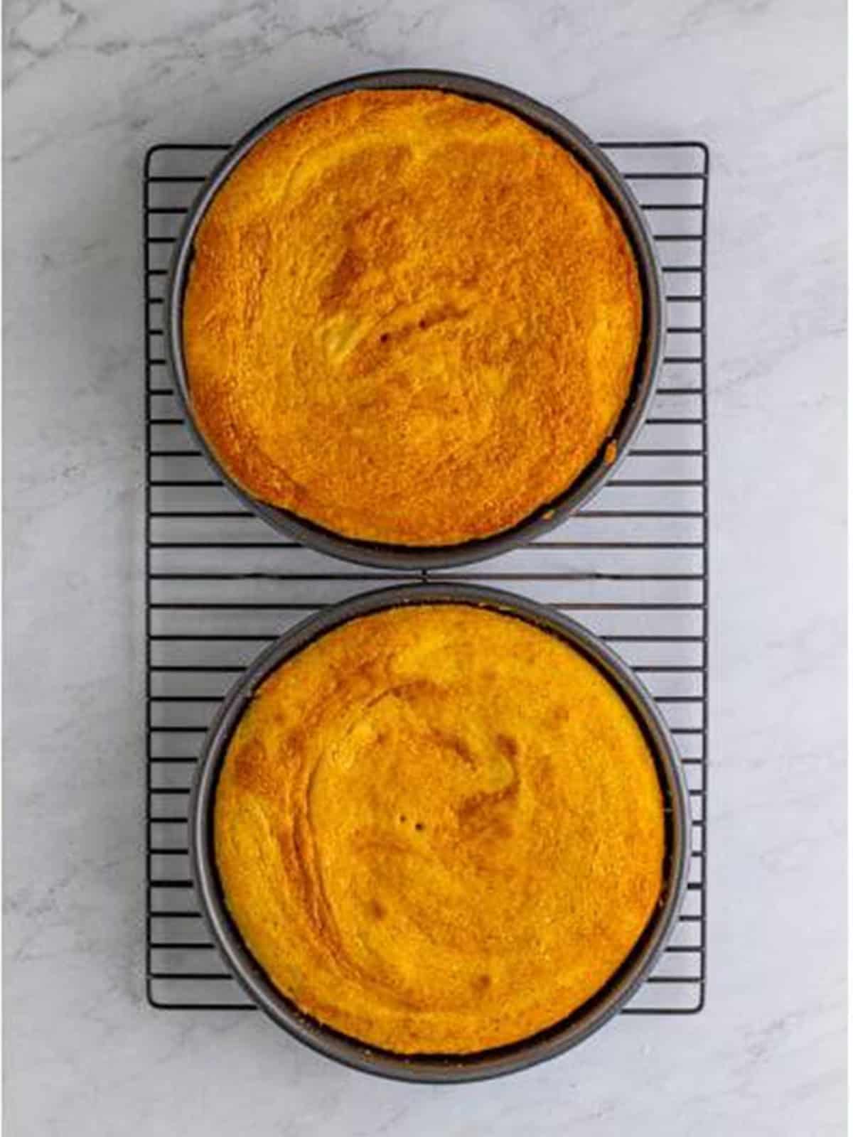 Two baked caramel cake layers cooling on a wire rack.