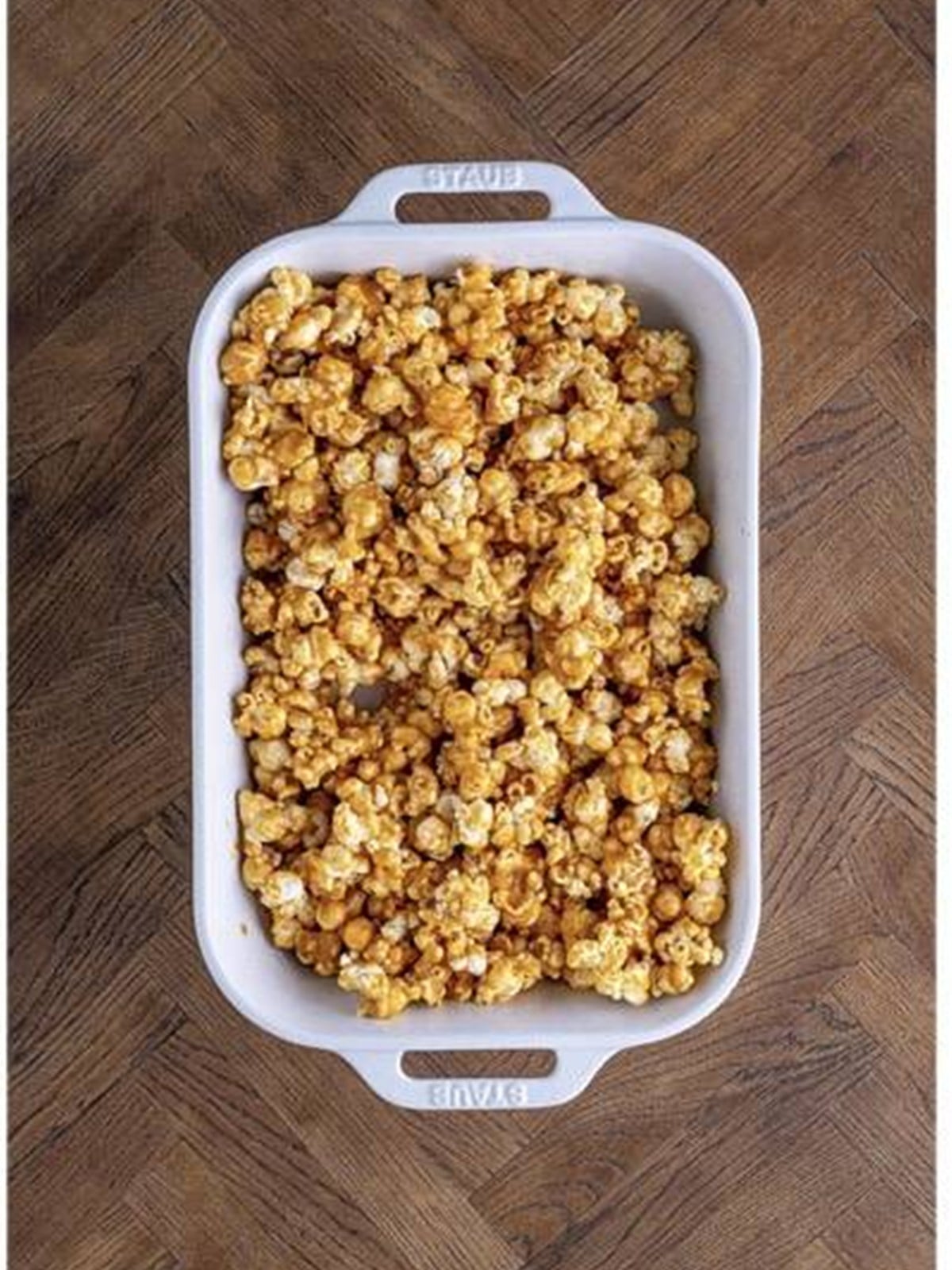 Coated caramel corn divided into a baking dish.