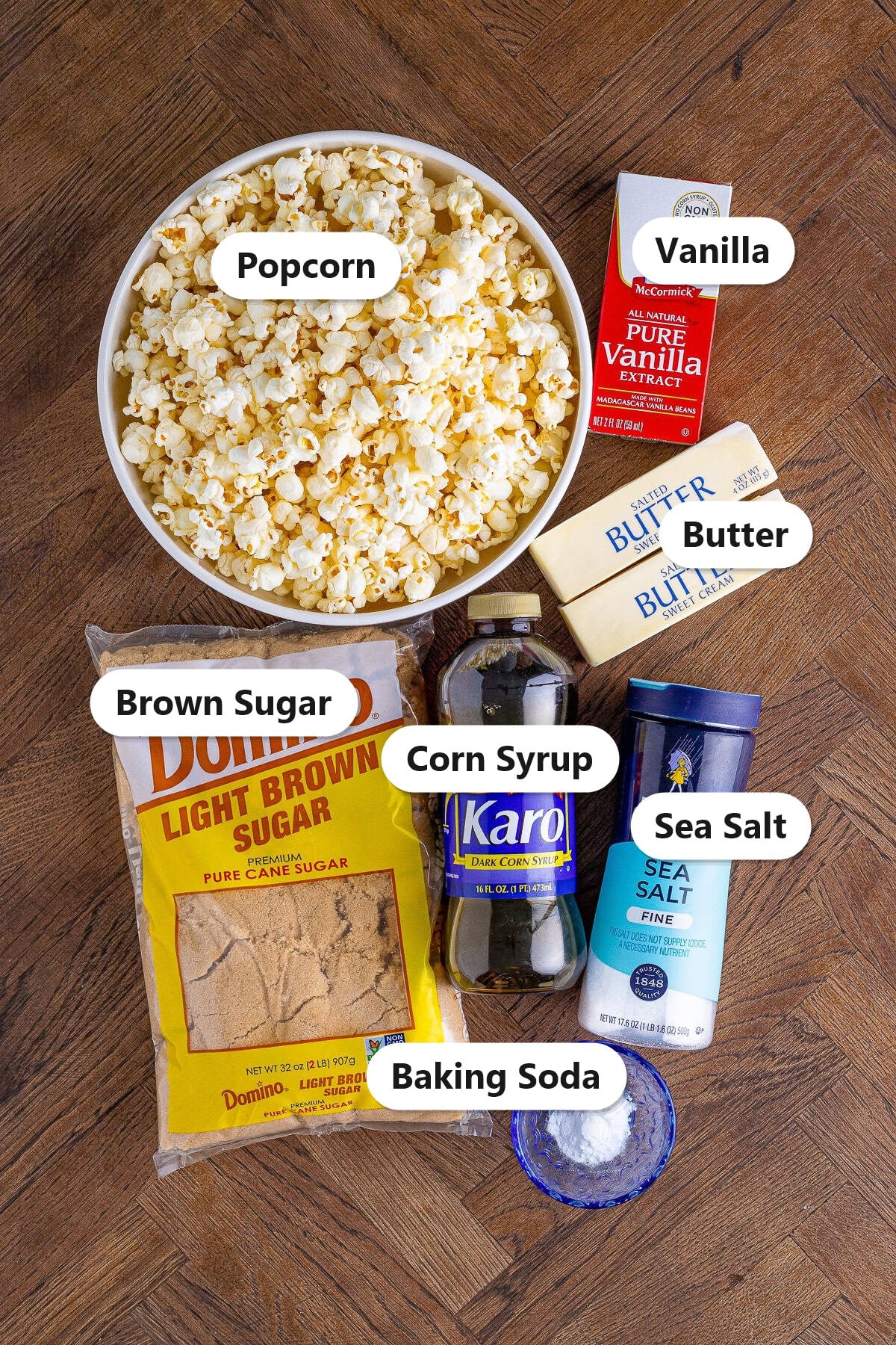 Labeled ingredients for caramel corn including popcorn, brown sugar, butter, corn syrup, vanilla, sea salt, and baking soda.