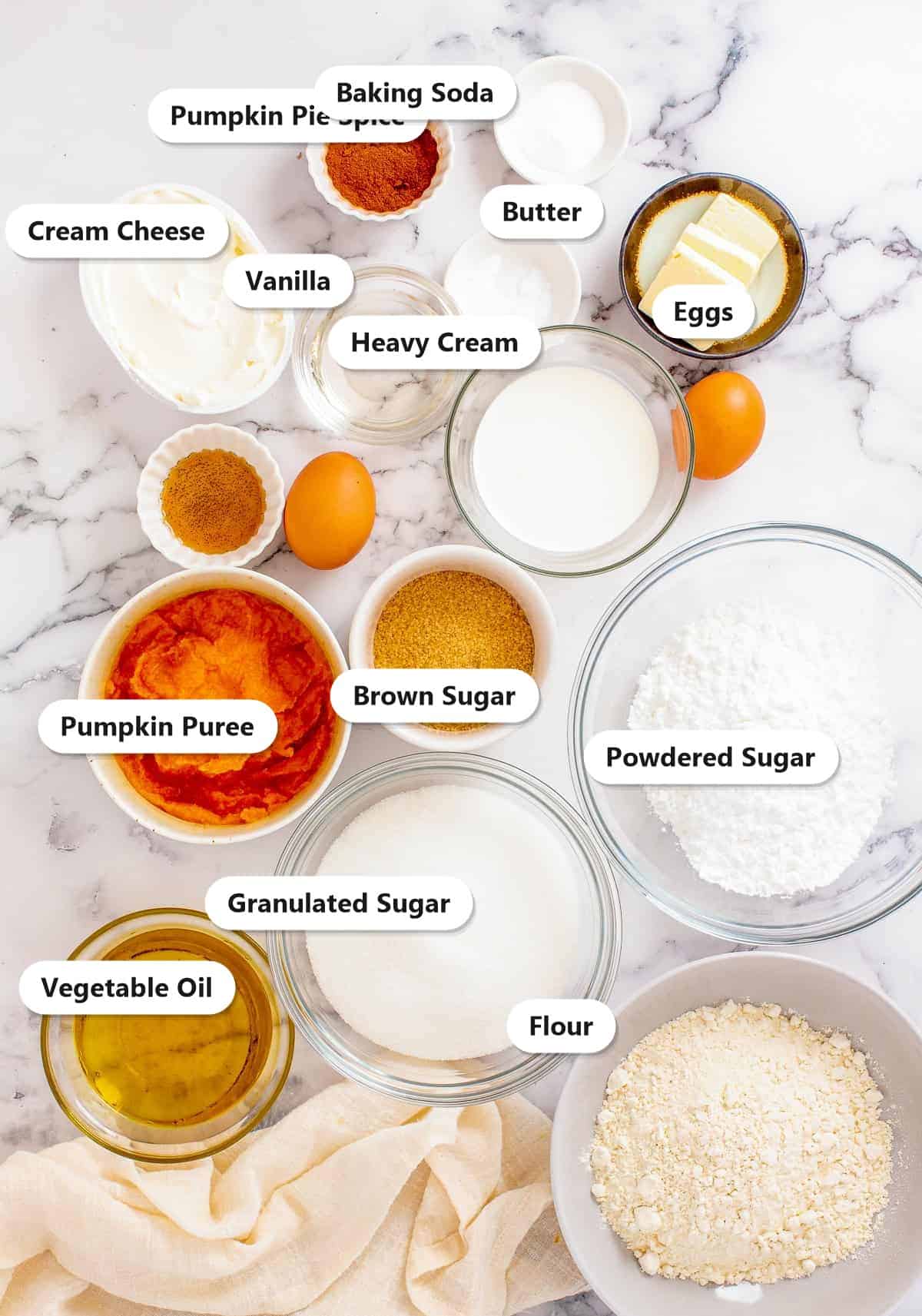 Labeled ingredients for caramel pumpkin sheet cake including pumpkin puree, flour, sugars, cream cheese, butter, and pumpkin pie spice.