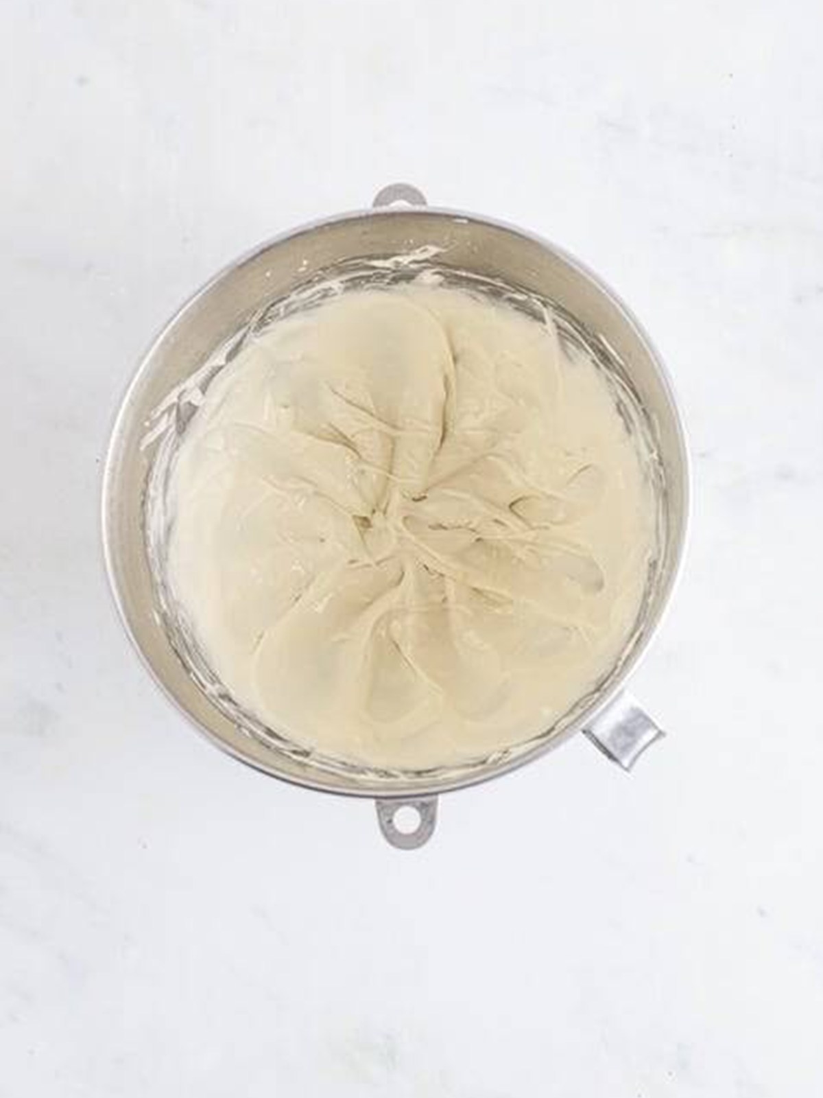 Whipped cream cheese glaze for carrot bundt cake in a mixing bowl.