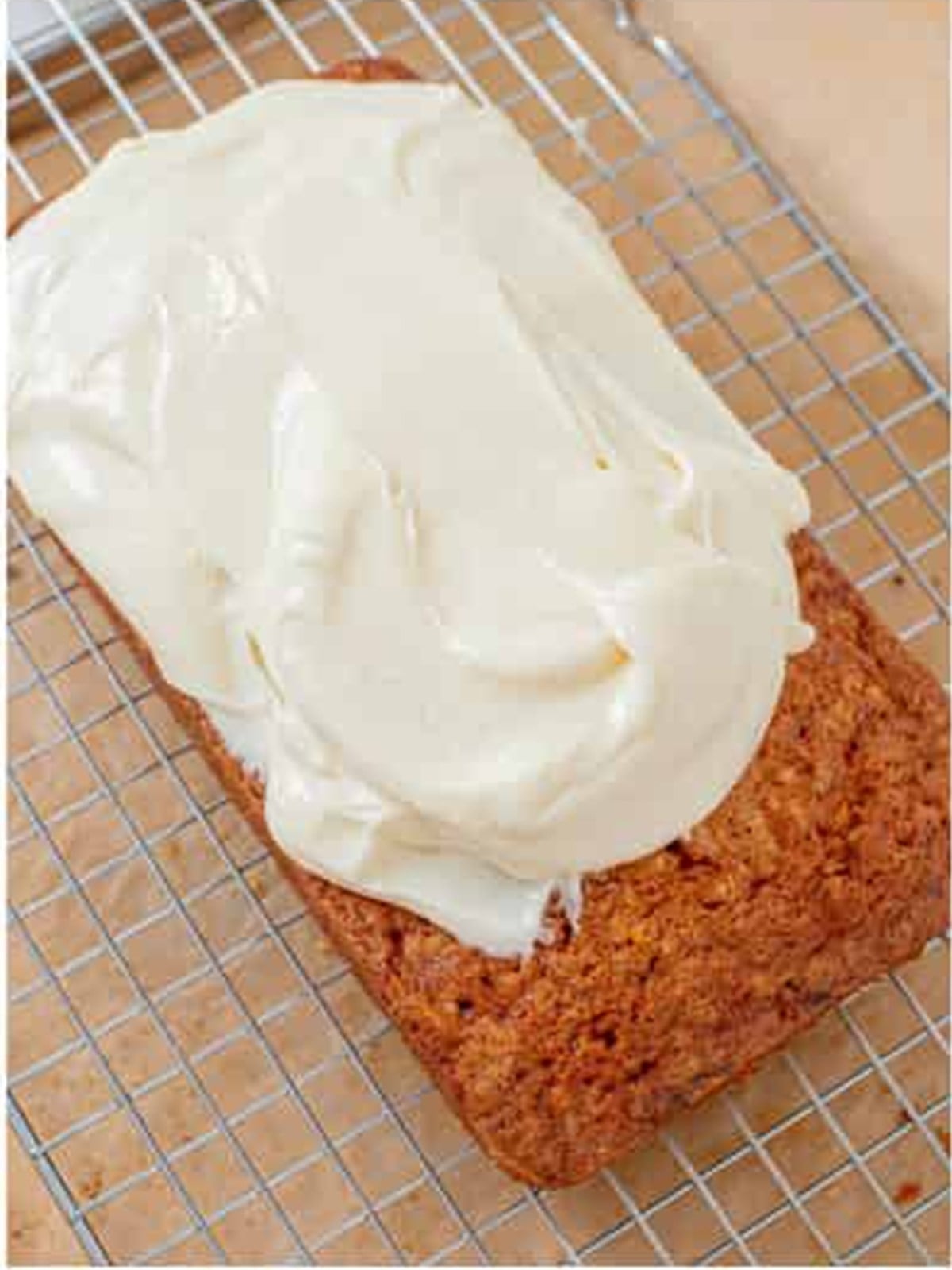 Cream cheese frosting spread over the cooled carrot loaf cake.