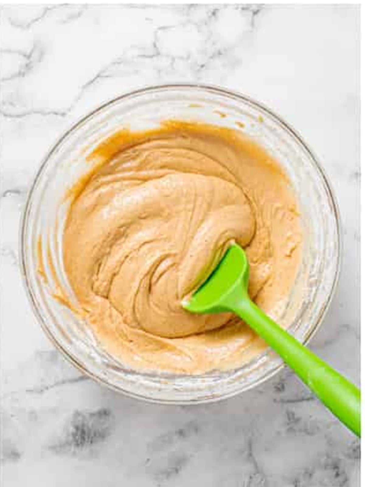 Carrot cake batter mixed together with a green spatula.