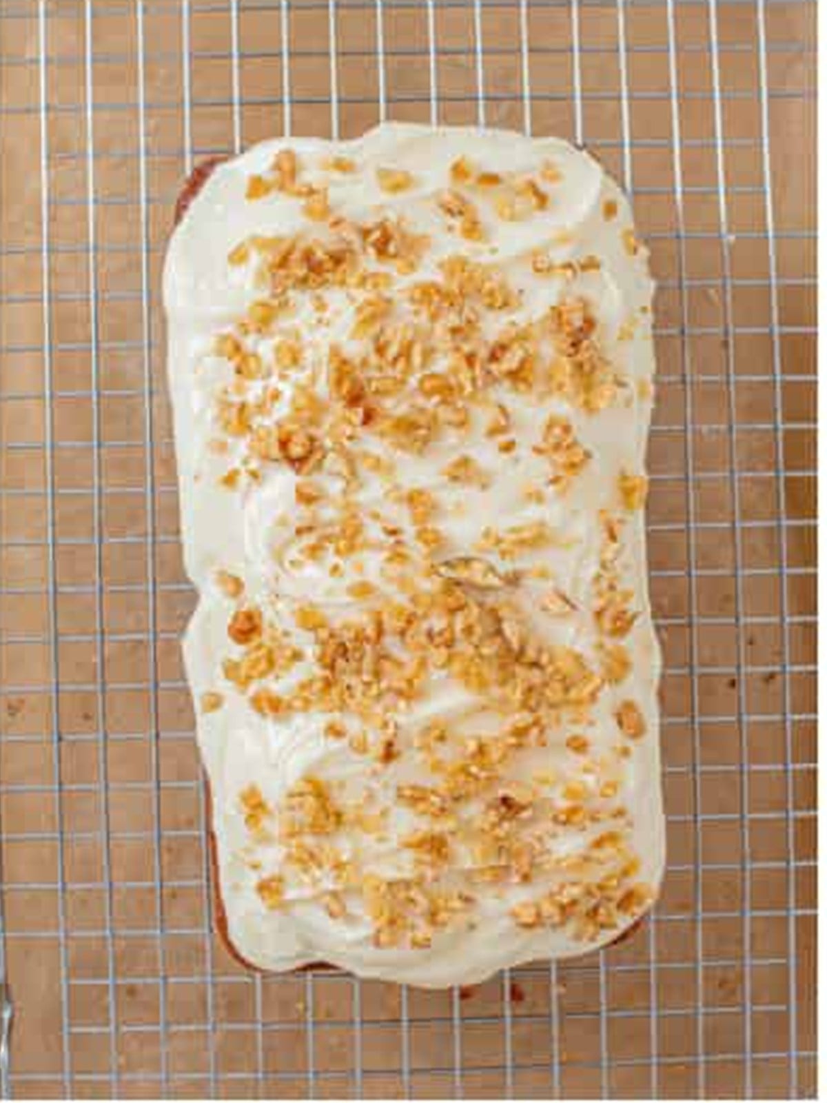 Frosted carrot loaf cake topped with chopped walnuts.