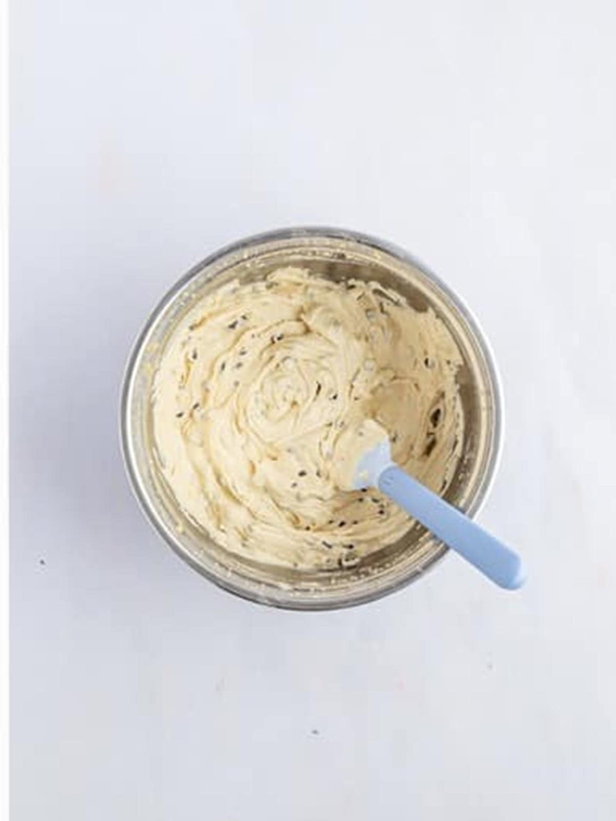 Fluffy cookie dough frosting with mini chocolate chips in a glass bowl.