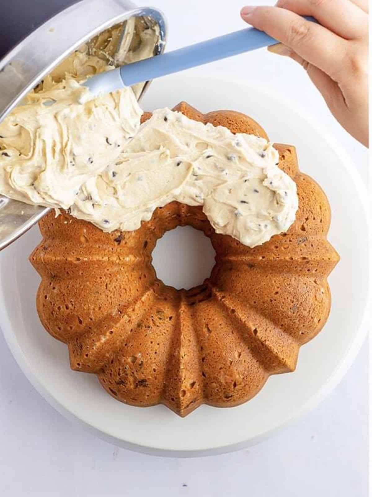 Cookie dough frosting being spread over a cooled chocolate chip bundt cake.